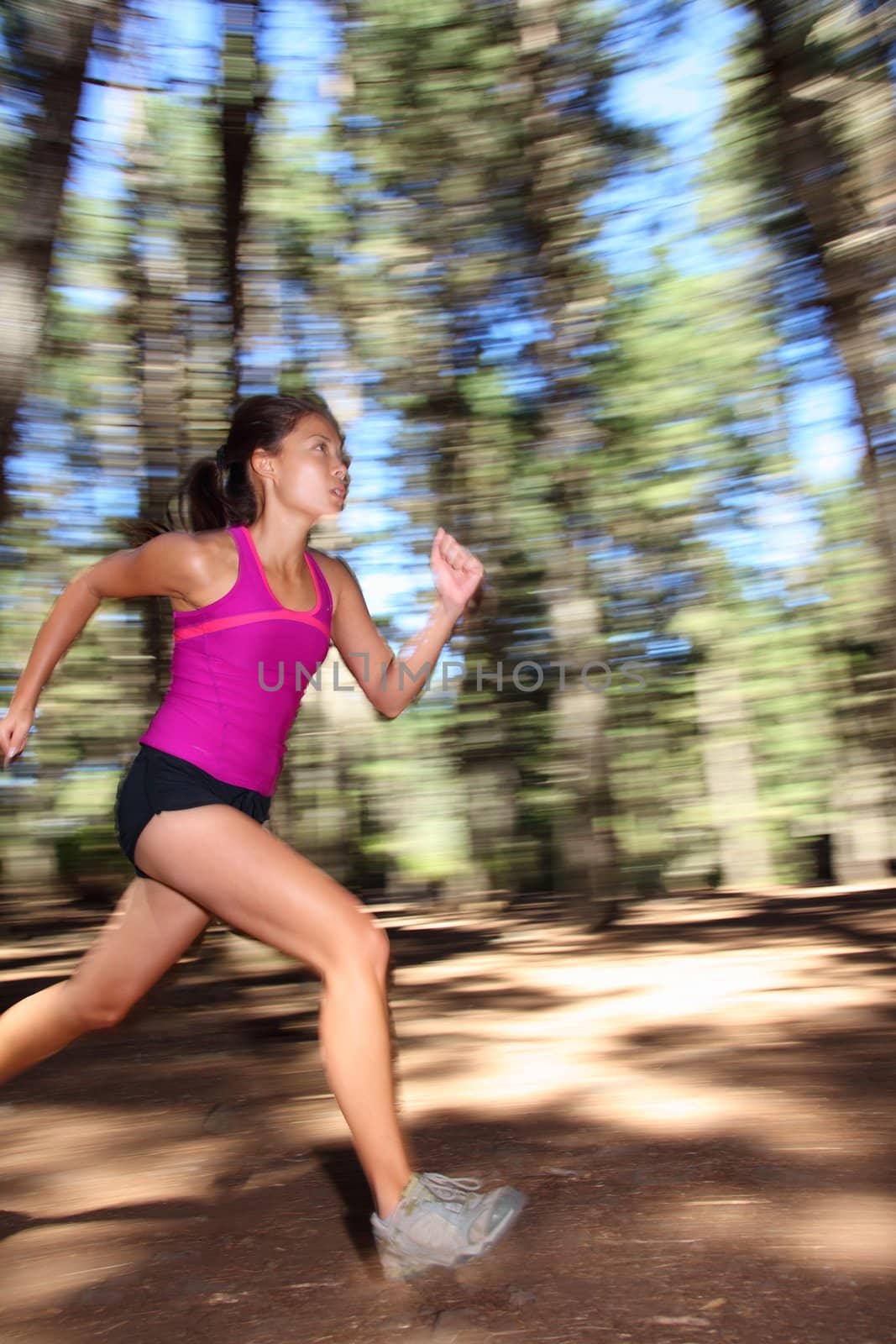 Runner, Female running fast in forest. Mot�on blurred image of beautiful Asian / Caucasian woman athlete sprinting outdoors in tank top - copy space.