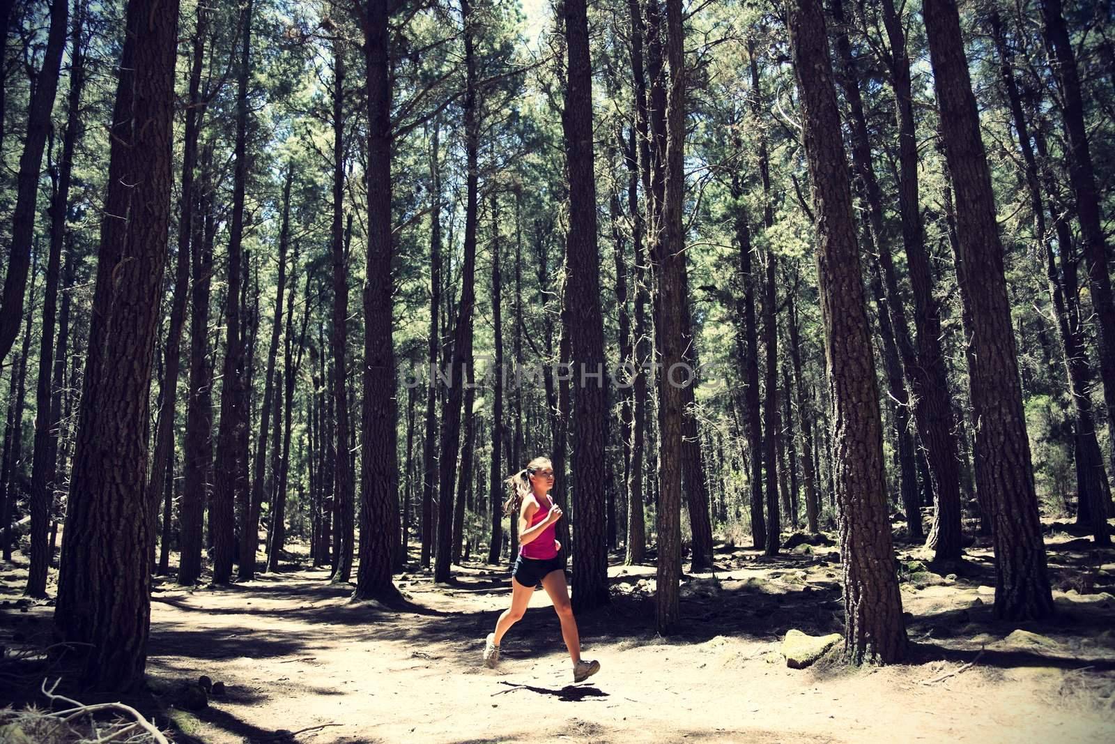 Running woman. Female runner running in forest. Beautiful Asian / Caucasian woman athlete jogging outdoors in beautiful forest with lots of mood / atmosphere and copy space. 