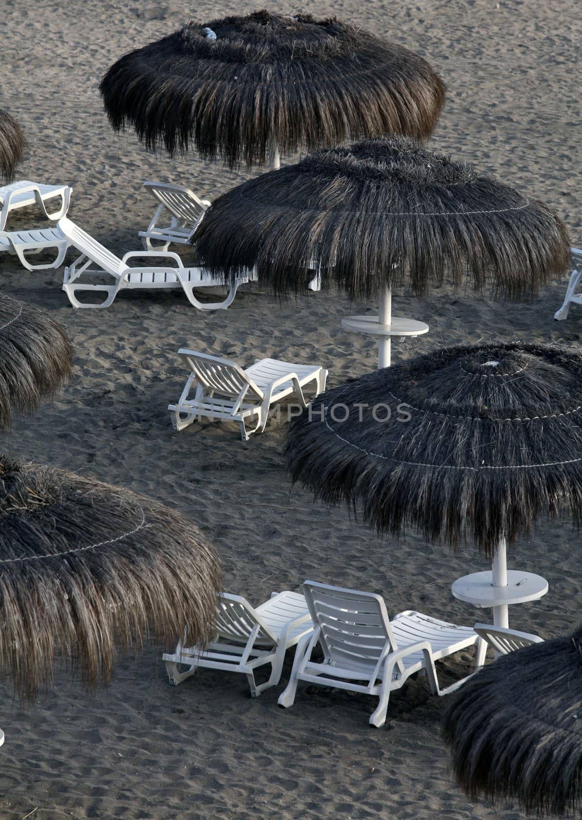 Beach with strawy umbrellas and white plastic chairs on Costa Adeje, Tenerife