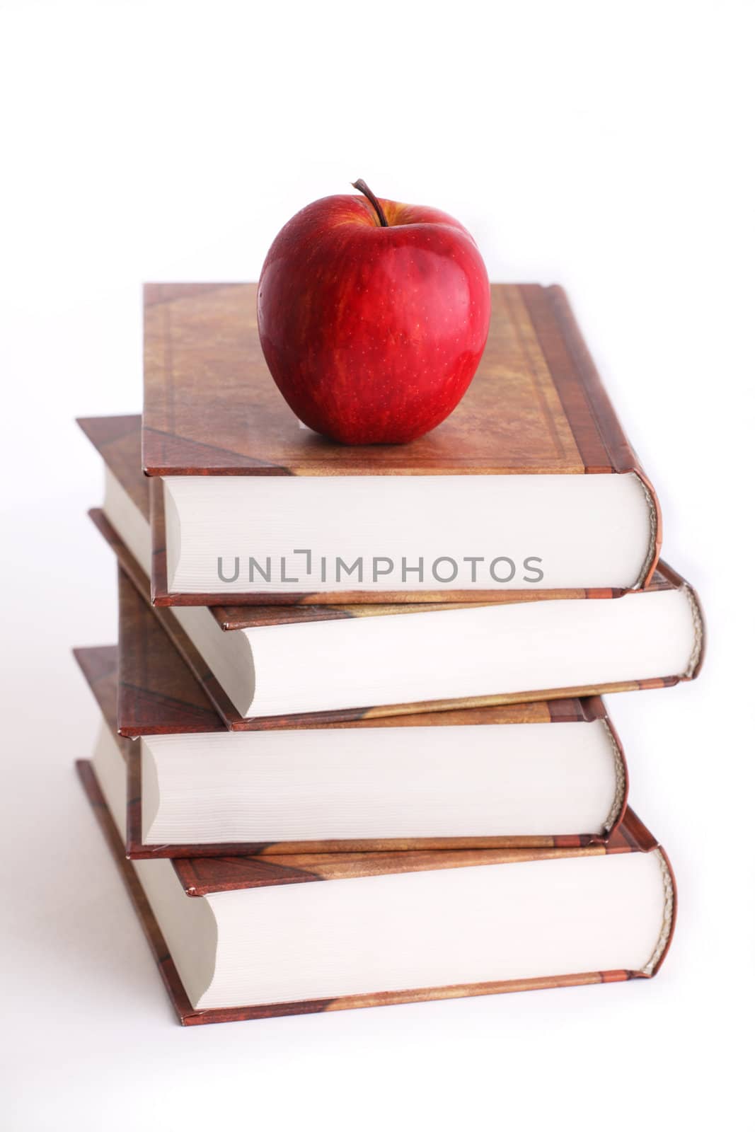 Red apple on the stack of the books on white background