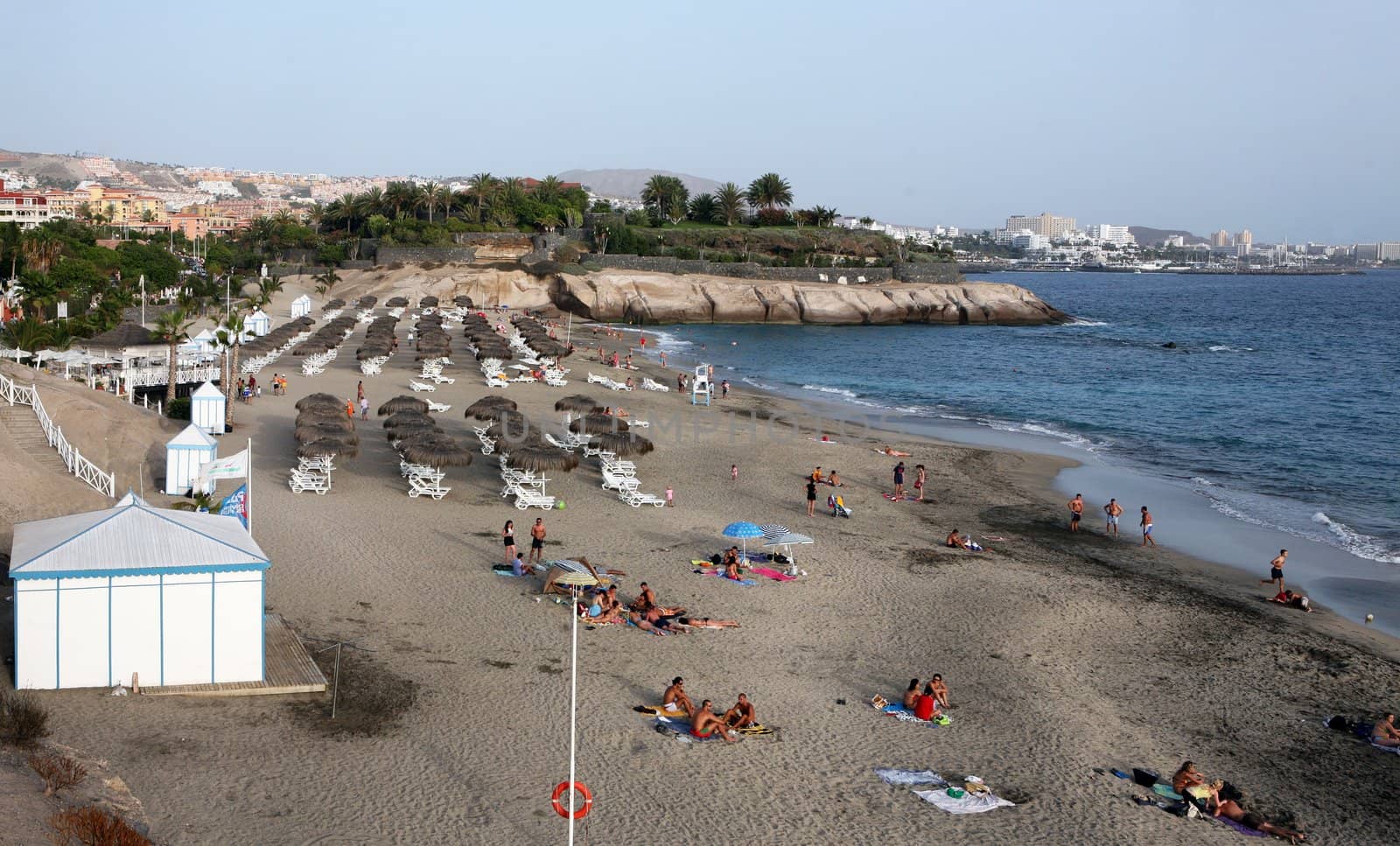 Beach with strawy umbrellas and white plastic chairs on Costa Adeje, Tenerife