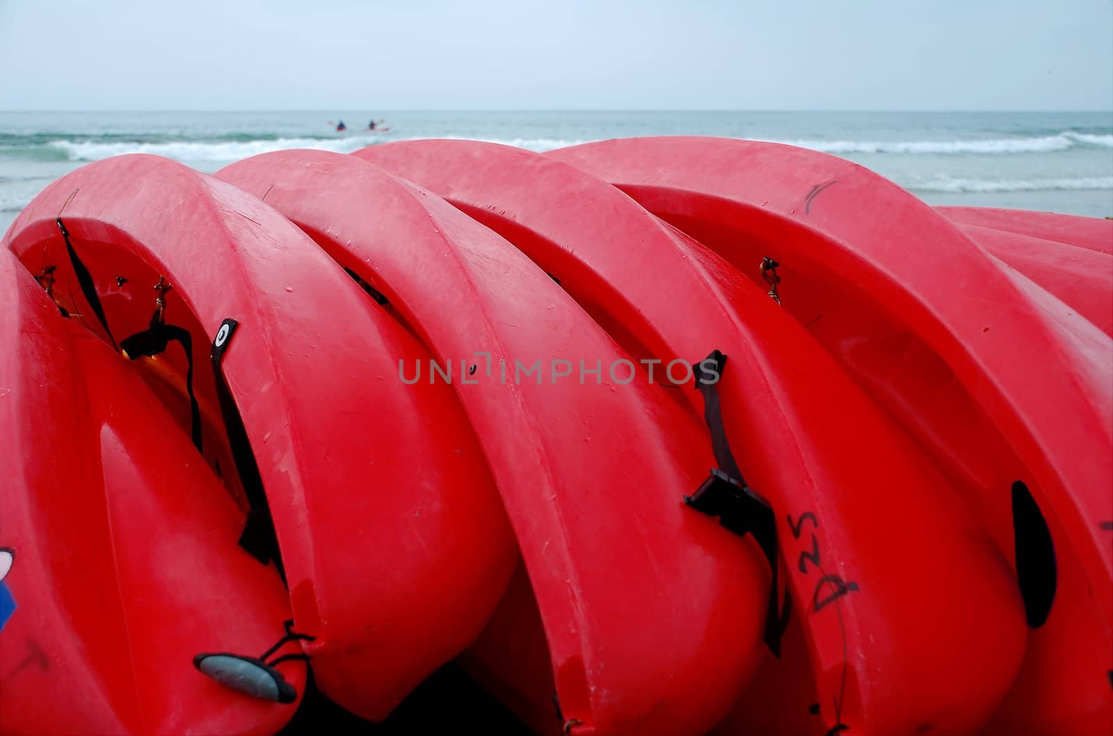 Row of bright red sea kayaks on the beach in California