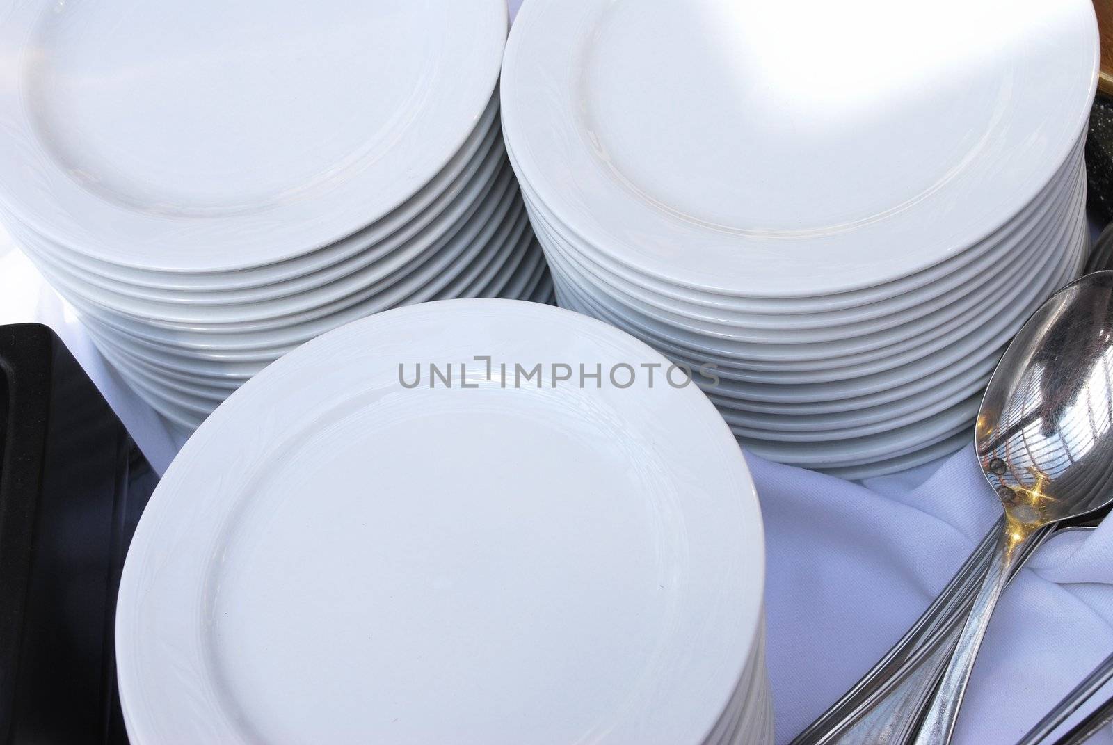 Three stacks of white dinner plates used at a catered event