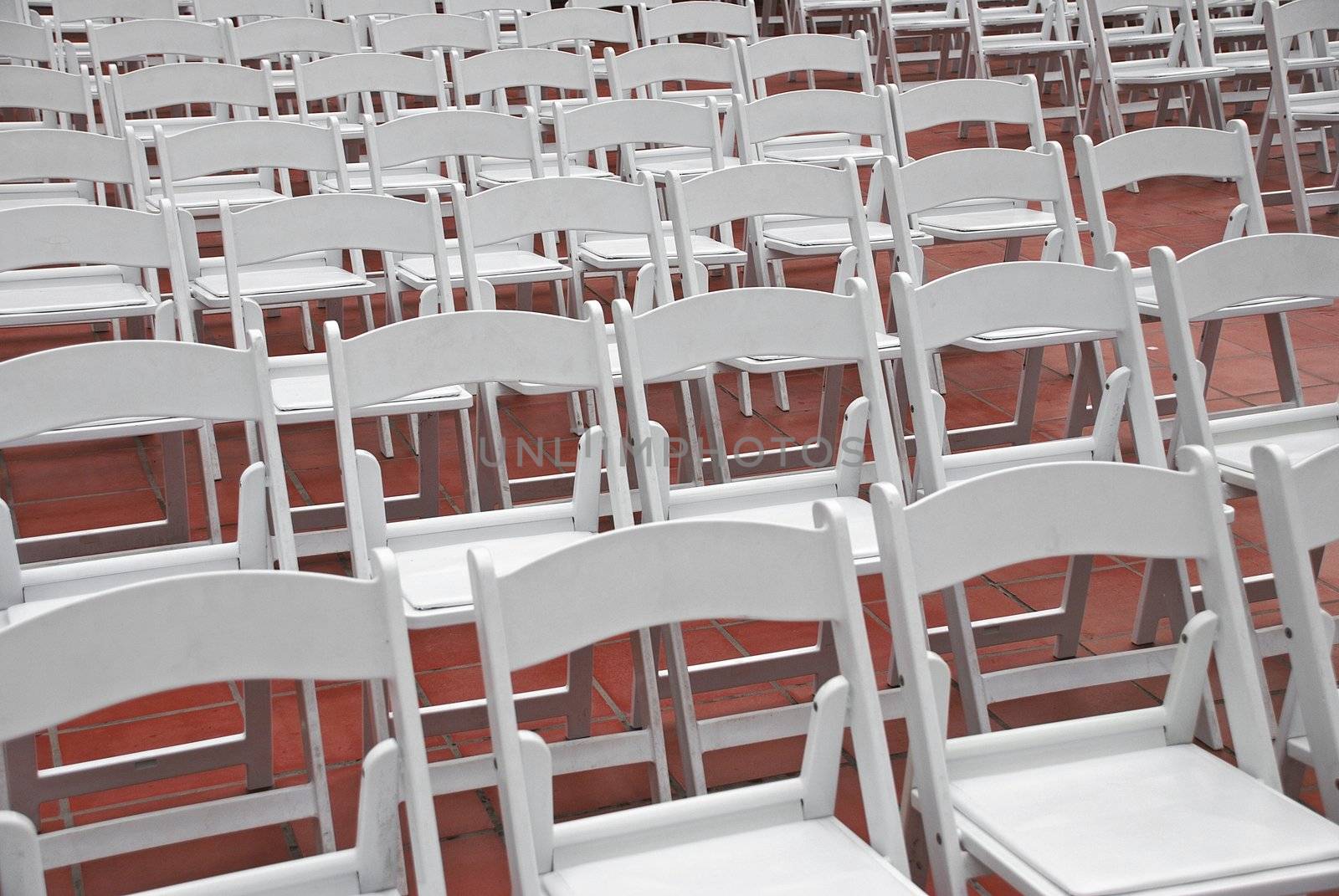 White chairs set up in rows for an outdoor wedding