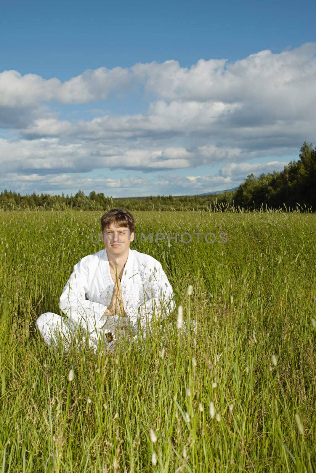 Young man meditates in a field by pzaxe