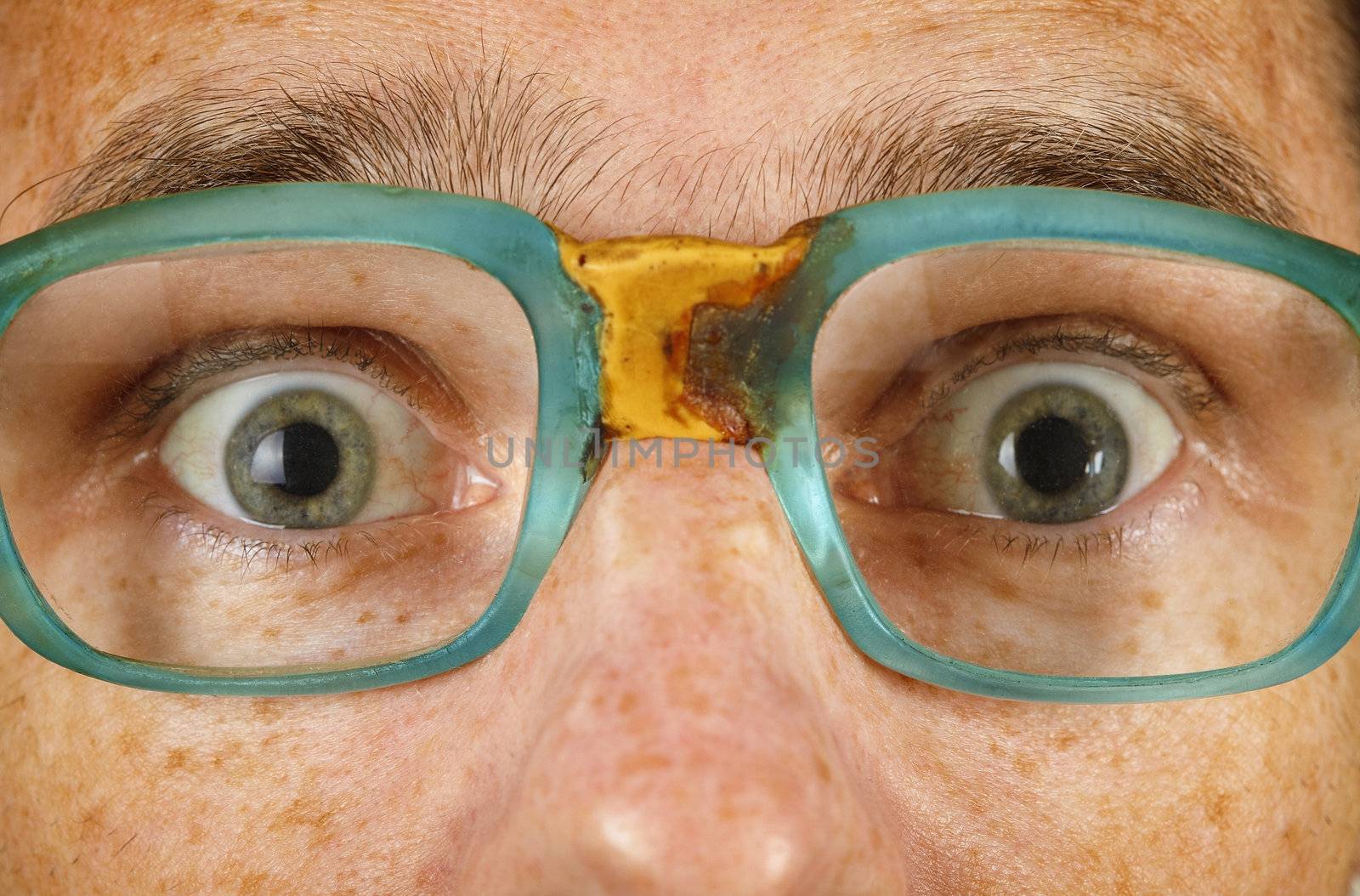 Eyes of the surprised person in old spectacles close up