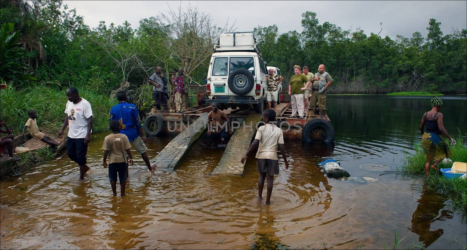 Crossing on a raft. Through wild small river in Africa (Congo) people and cars are forwarded on a raft.