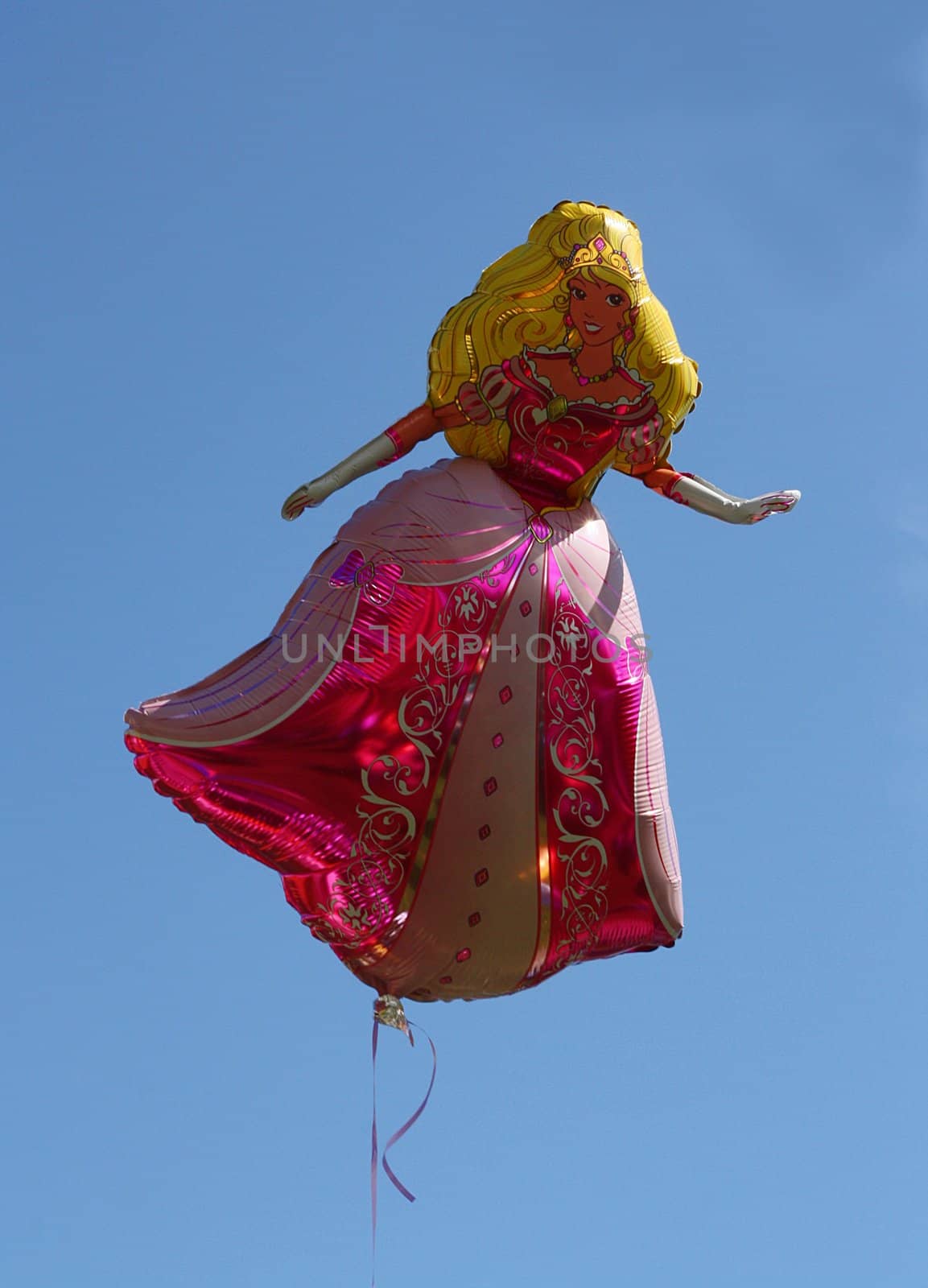 Helium balloon shaped as a princess hovering against a blue sky