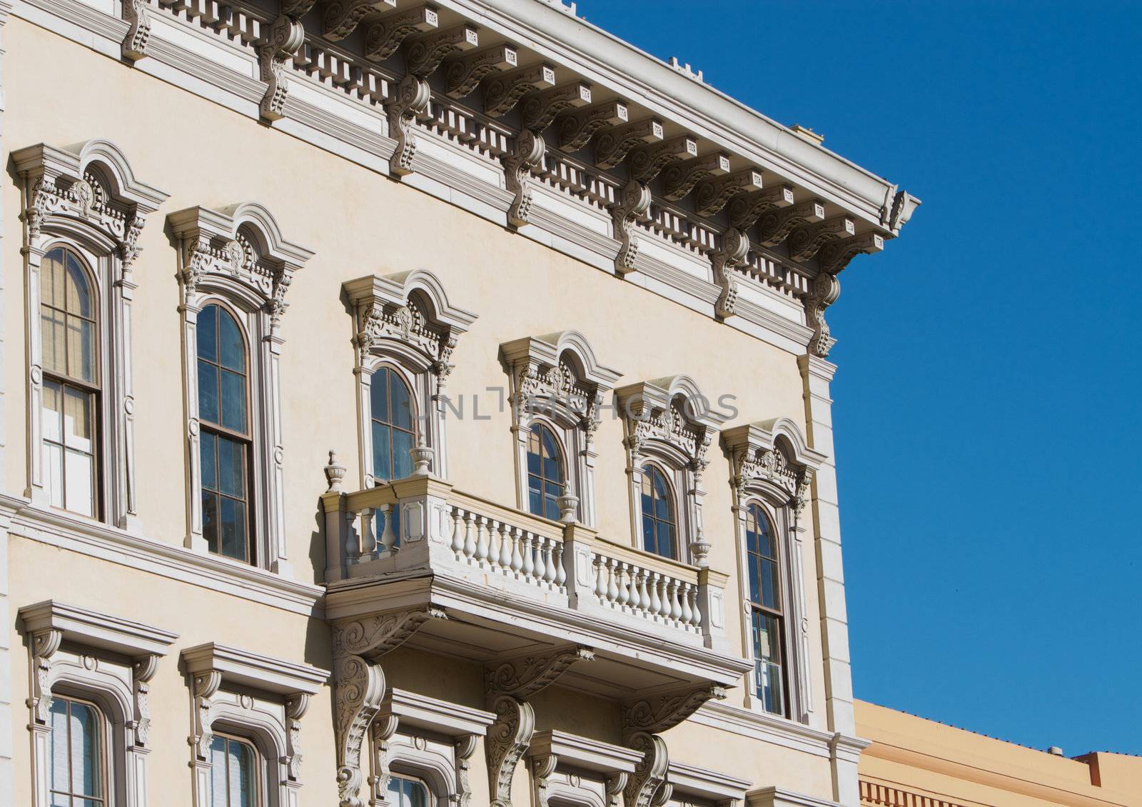 1800s gold country tan ornate building face with balcony and blue sky