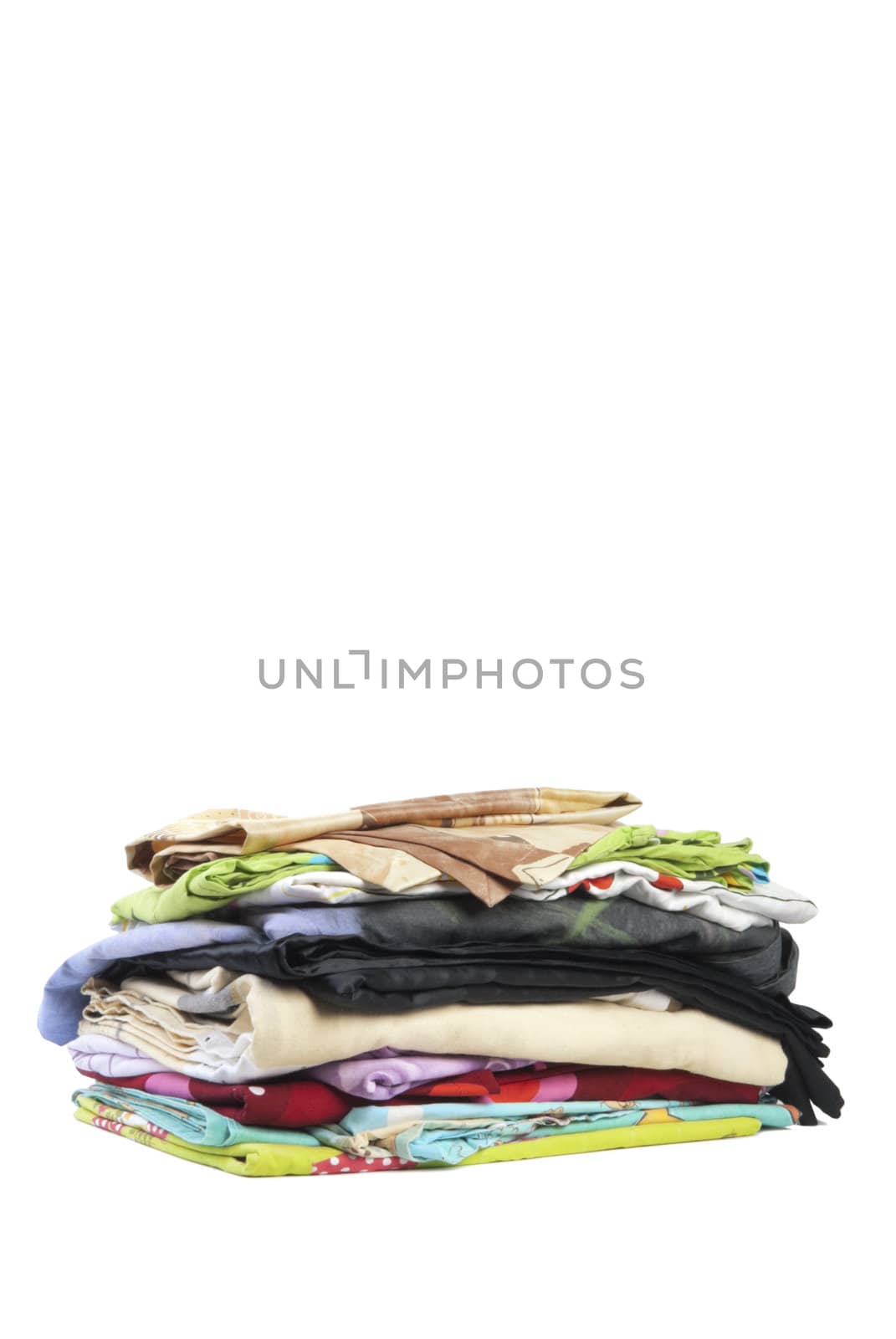 Colorful stack of dirty bed-clothes is ready for laundry. Isolated on white background
