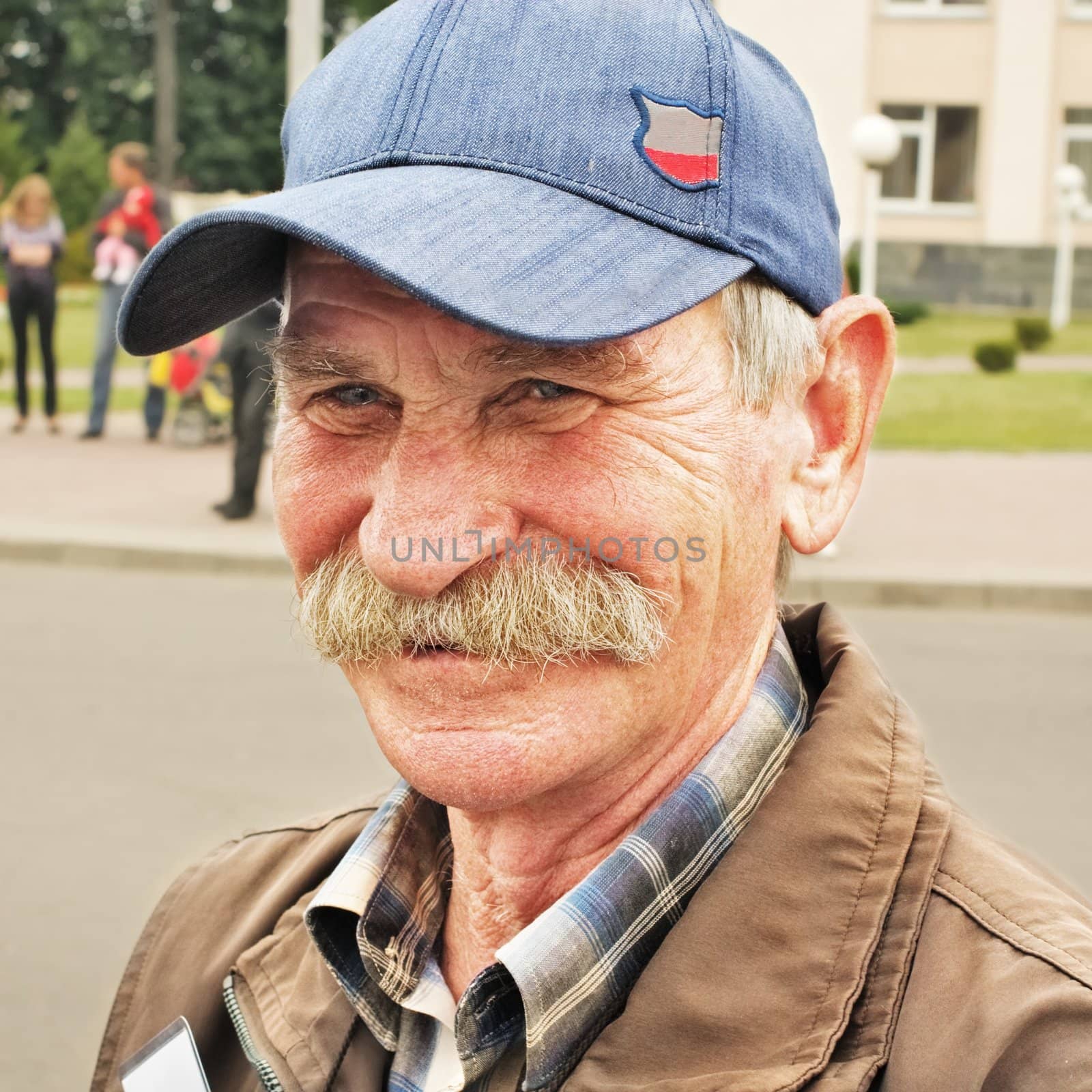 Portrait of the smiling elderly man in a cap