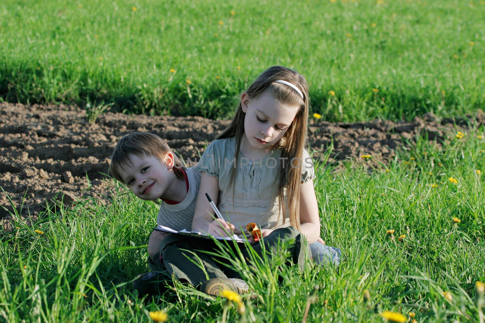 Brother and sister enjoy summer time in the green grass.