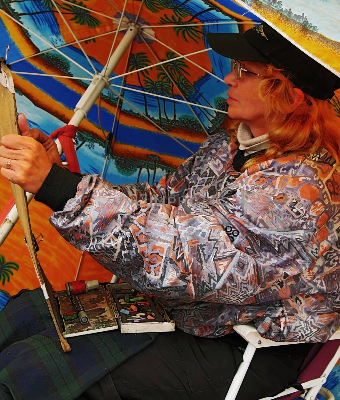 The street artist draws under an umbrella