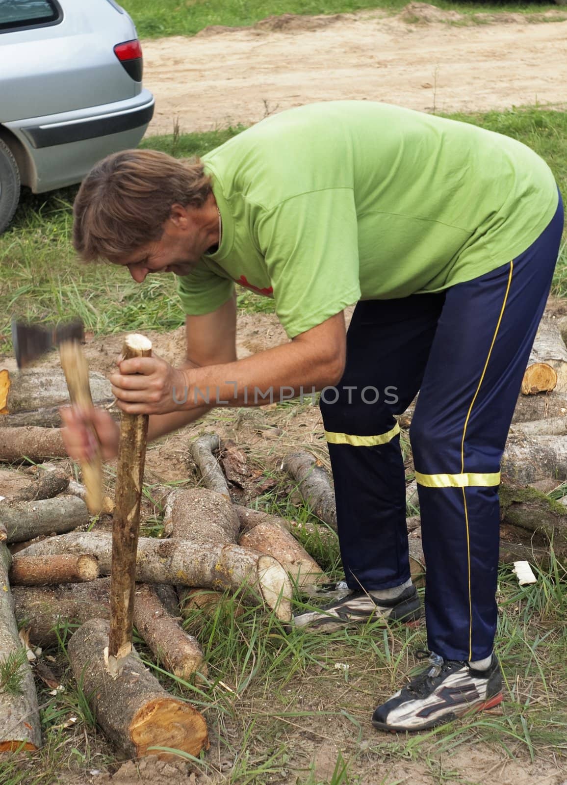 The man cuts a wooden peg on wooden logs