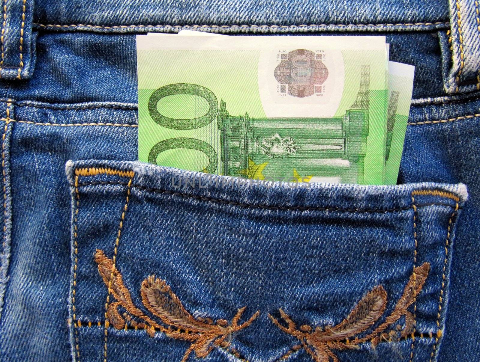 A couple of one hundred Euro bills in the back pocket of blue jeans.                             