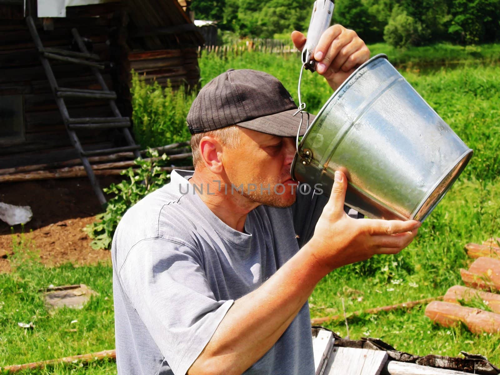 The man drinks water from a bucket