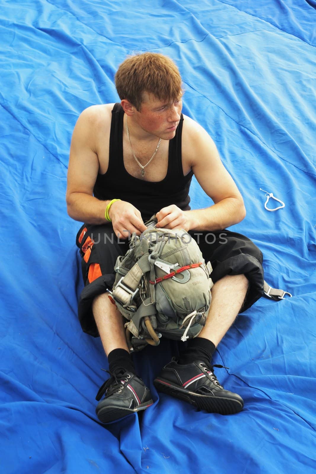 The serious guy in a black vest prepares a parachute for a jump