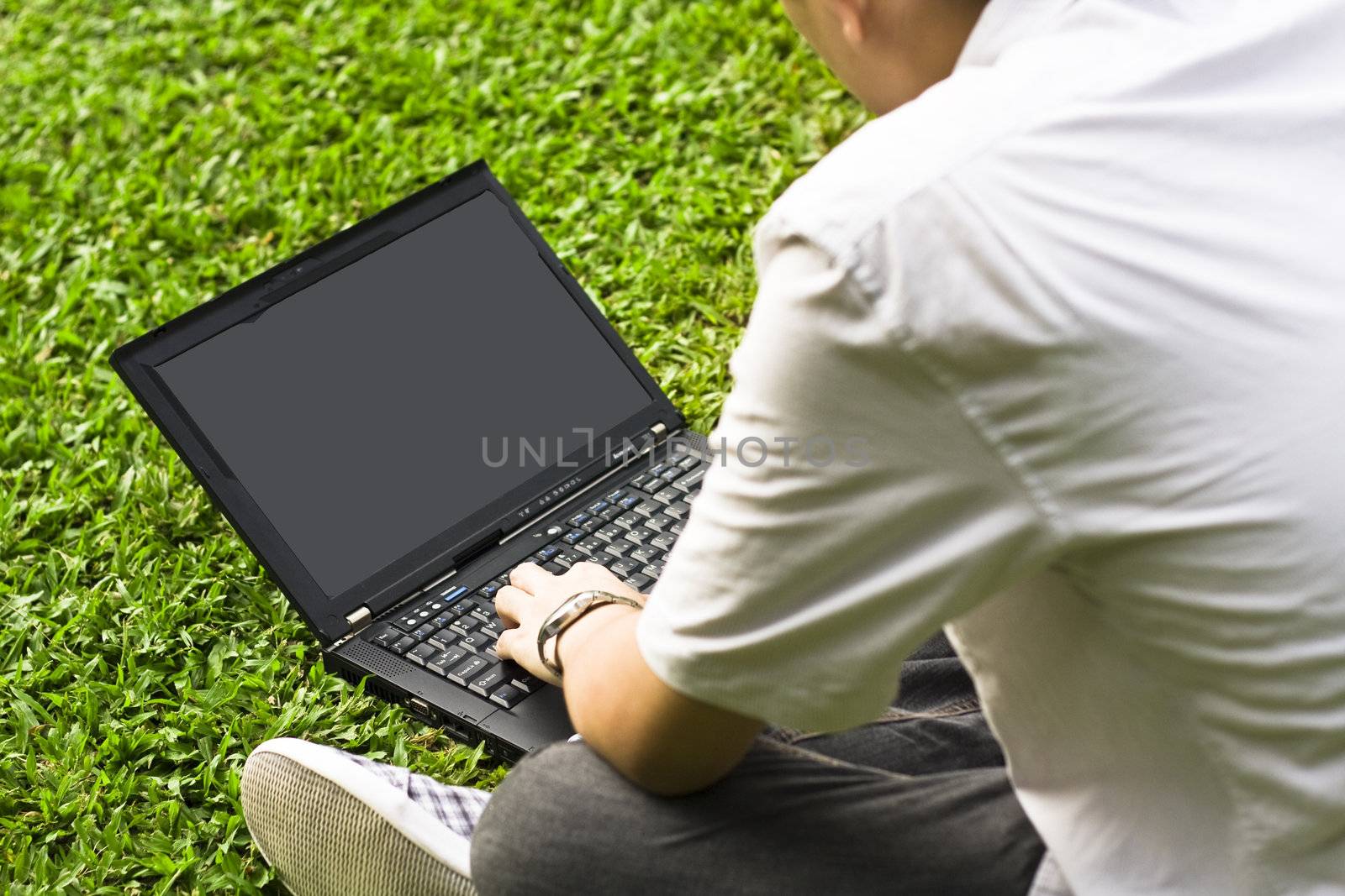 Man siting on the grass using laptop  by cozyta