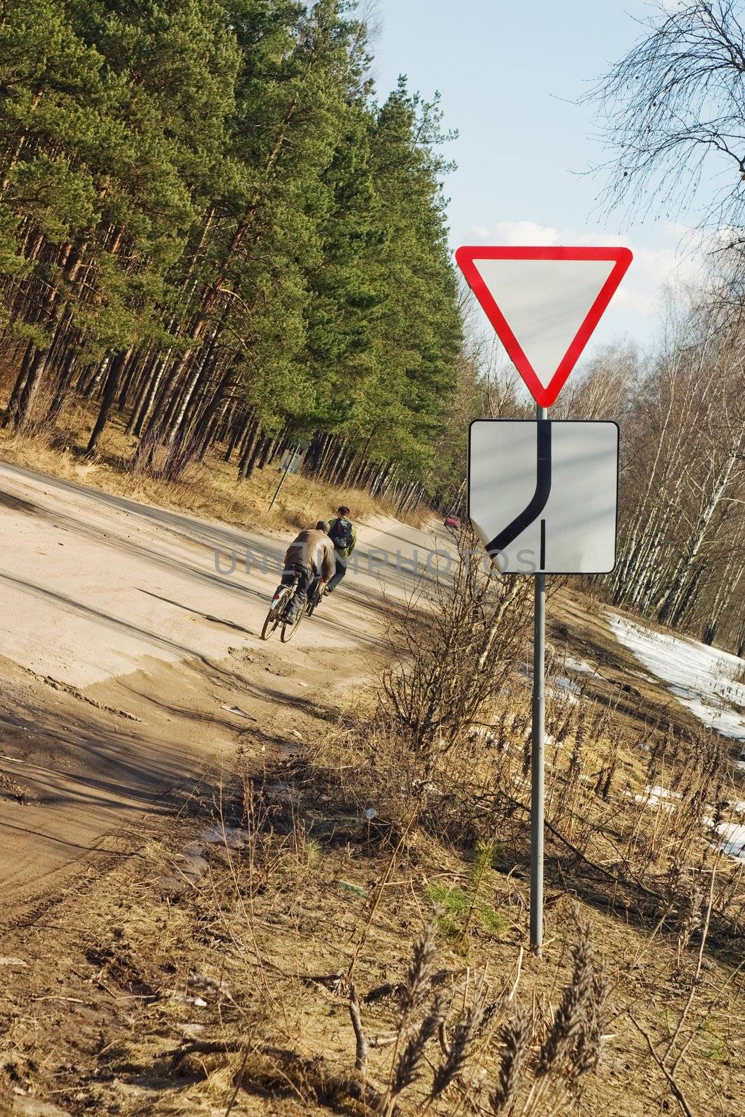 Bicyclists on move from soil road to the asphalt