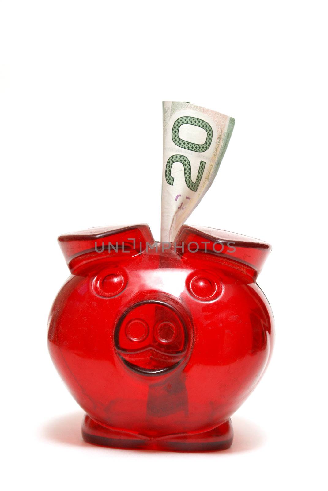 A red piggy bank with a twenty dollar bill for the money saving mind set.