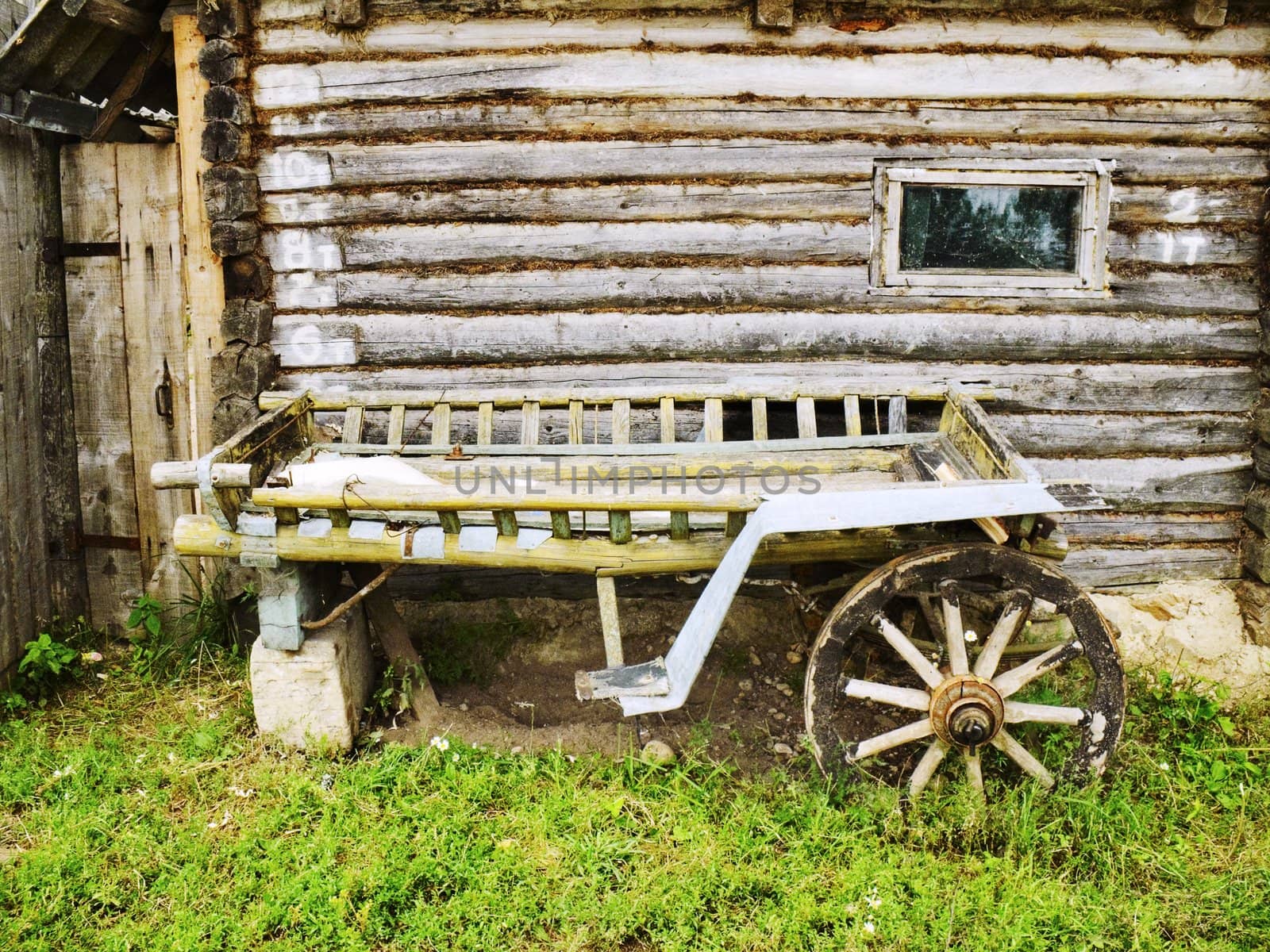 Old cart near the wooden house from logs