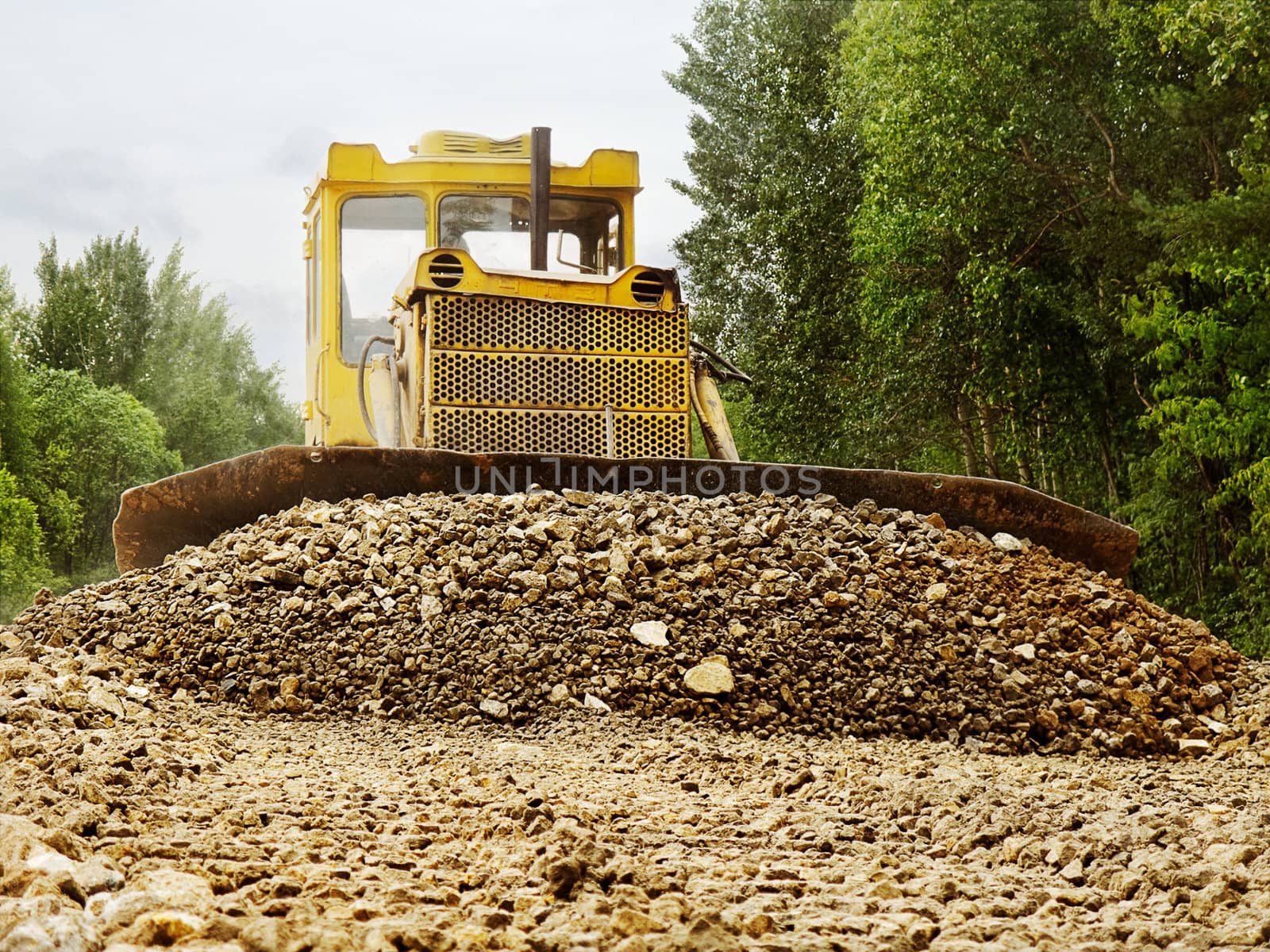 The bulldozer rakes up gravel for road alignment