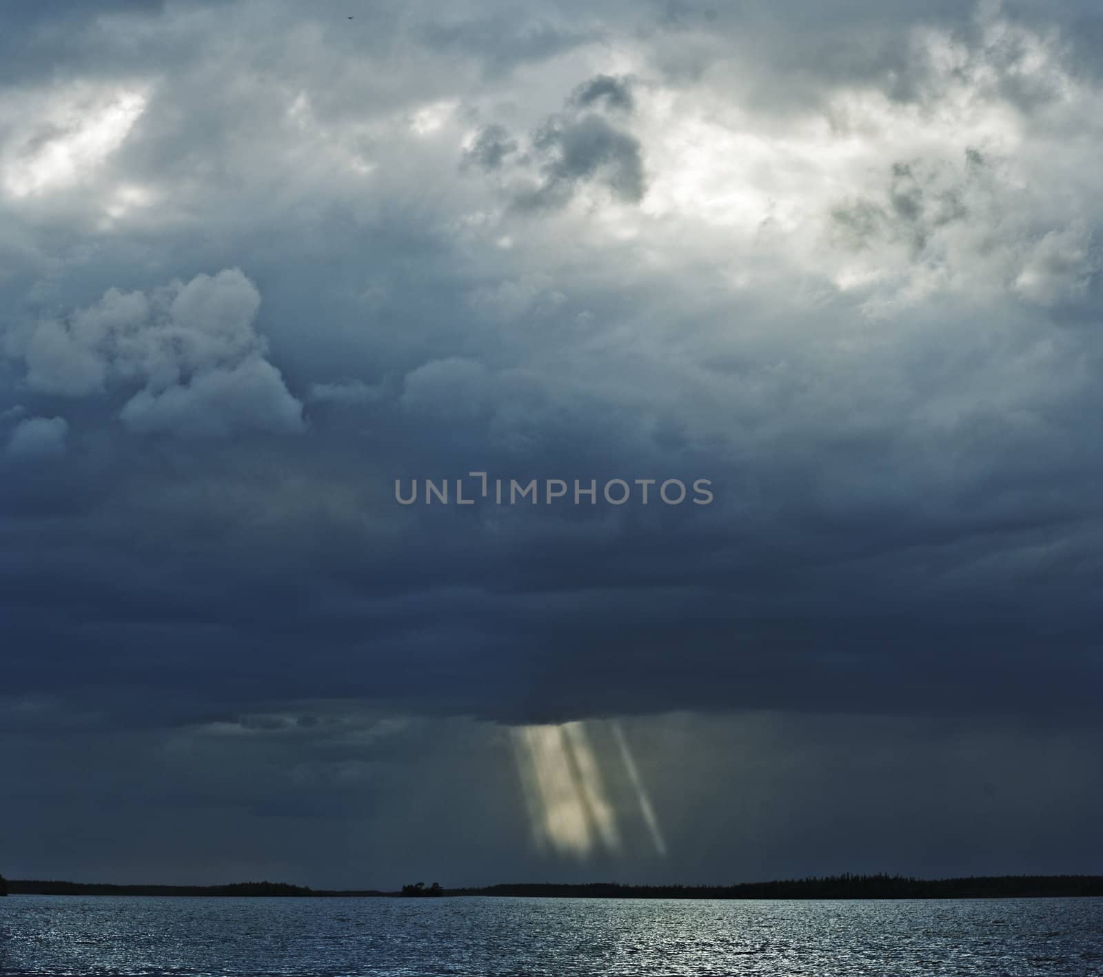 Thunderstorm over lake. Sun beams are visible through clouds