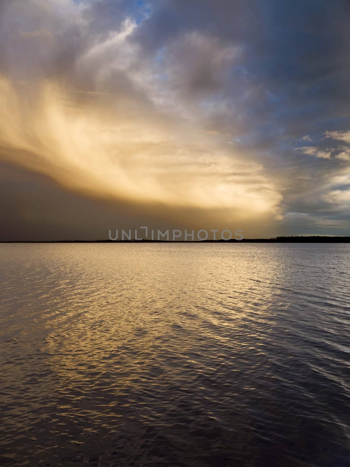 Thunderstorm over lake. Sun beams are visible on clouds
