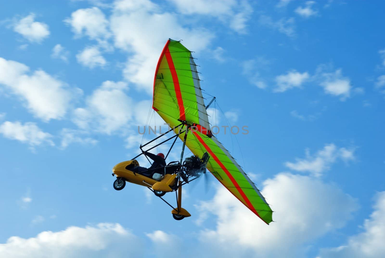 The motor hang-glider flies up in the blue sky