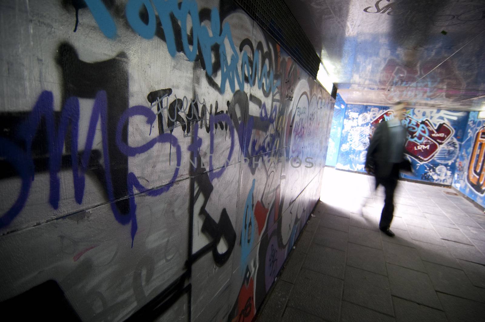 A man walk in a tunnel with graffiti