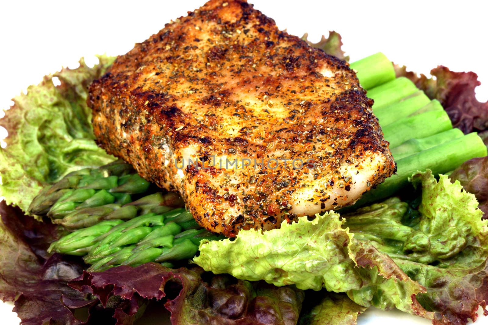 delicious grilled sea bass, seasoned with fine spices with asparagus and lettuce bed 