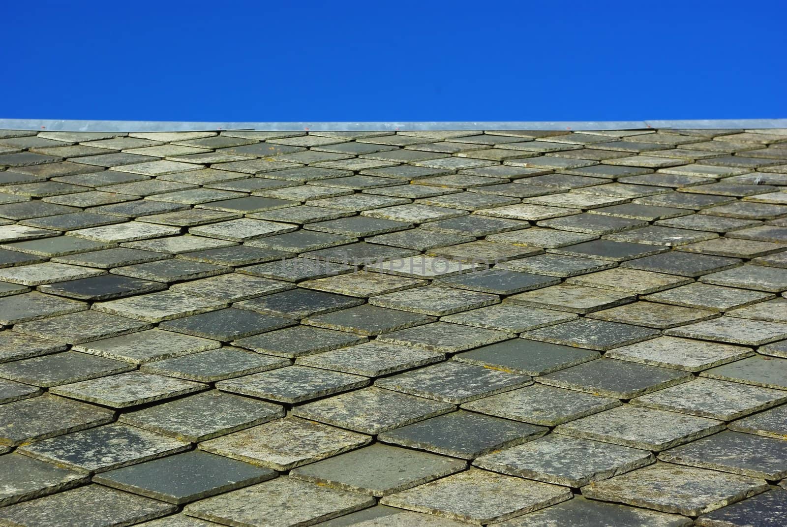 Roof made of plates of slate on blue sky