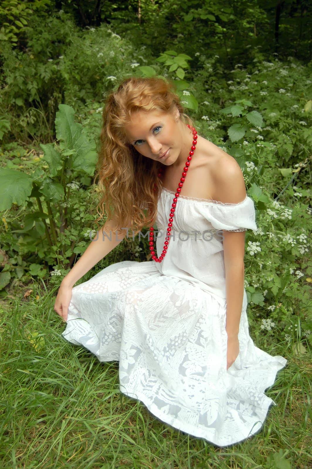 Beautiful red-head girl among fresh green forest