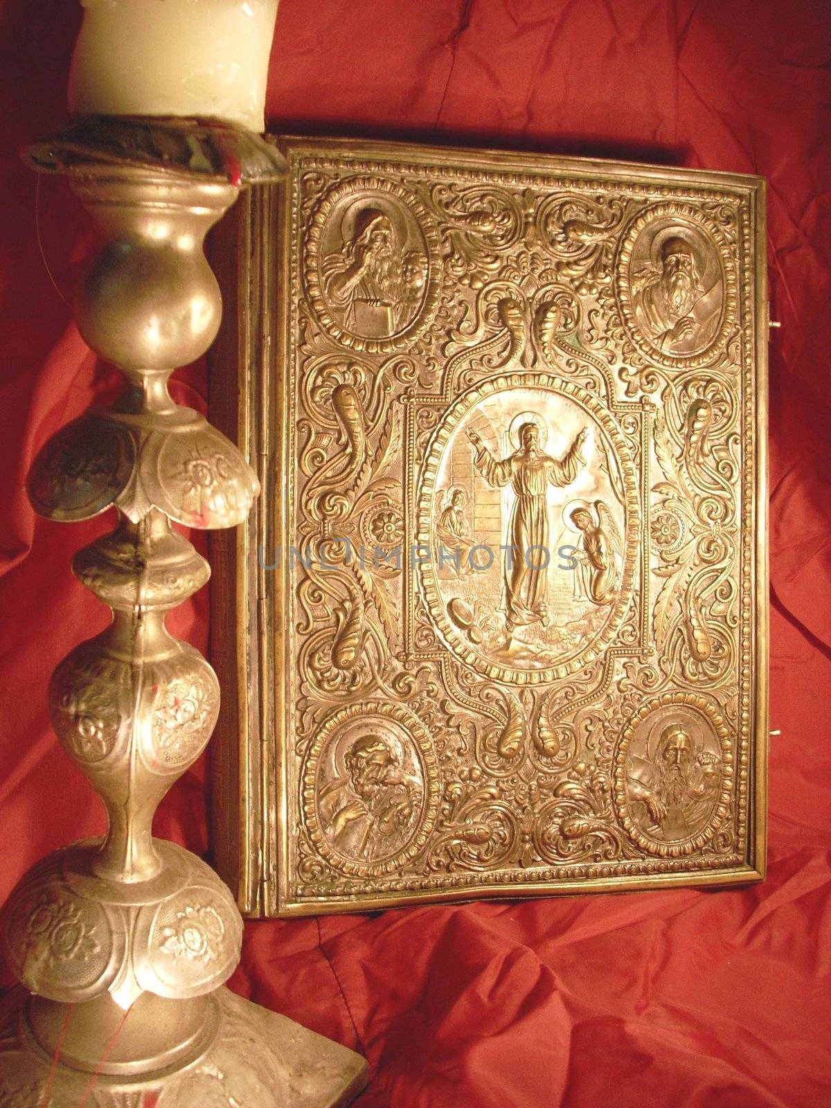 very old Bible, candlestick and icons on a Red shining silk background