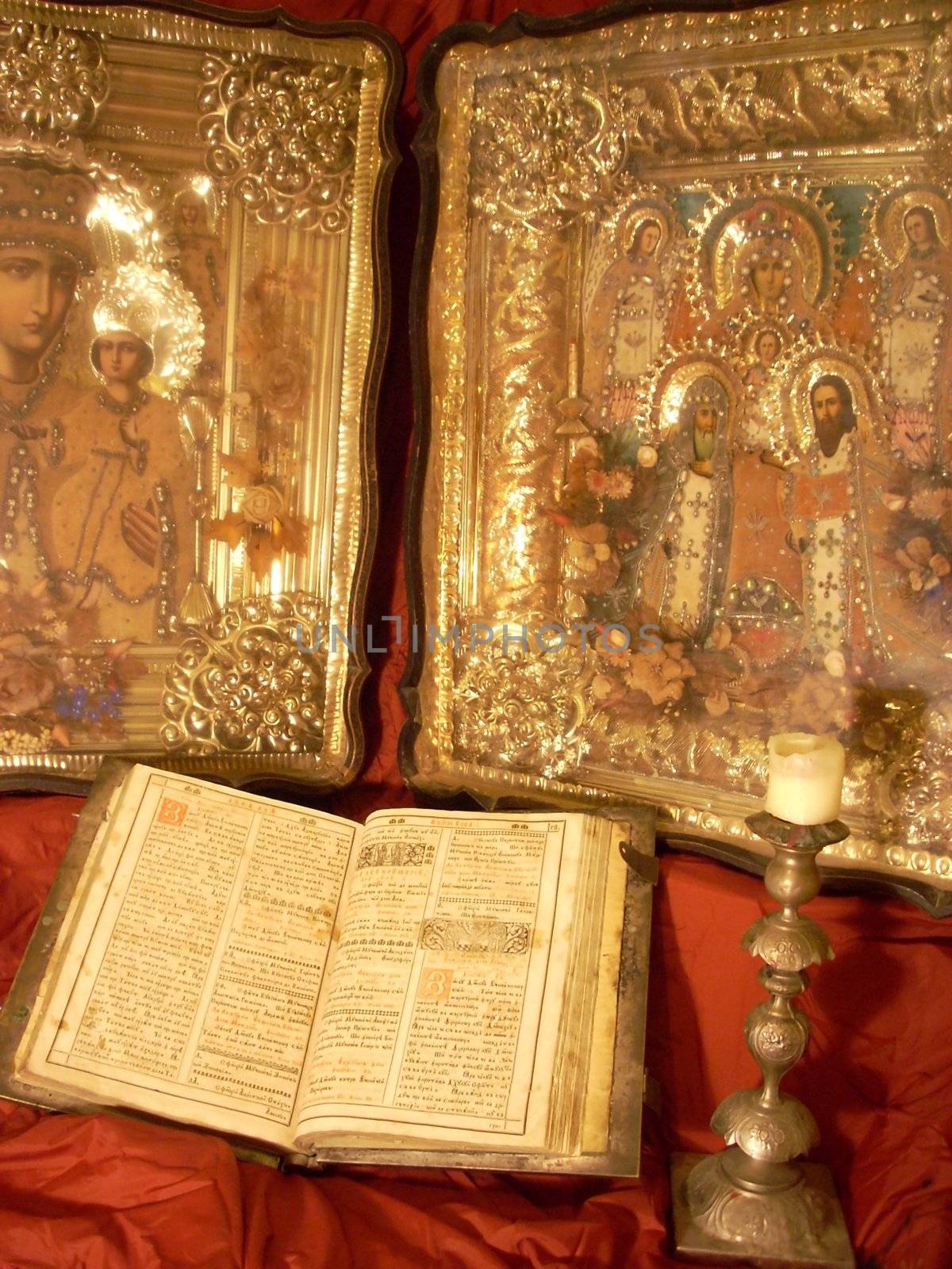 very old Bible, candlestick and icon on a red shining silk background