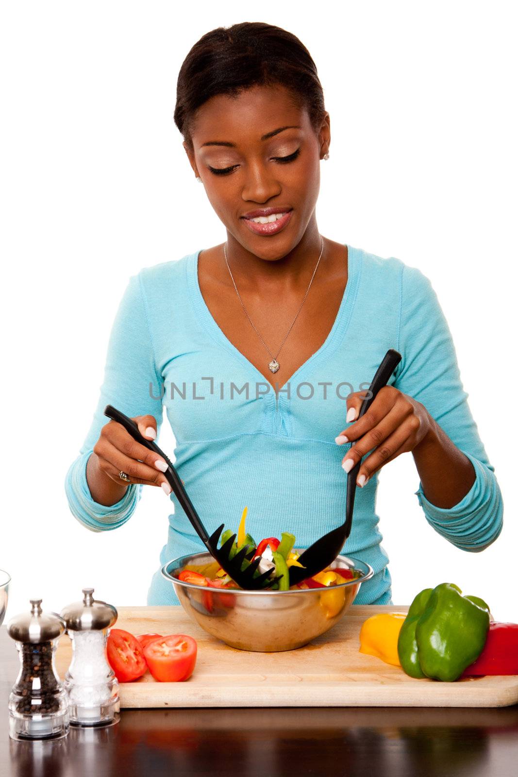 Beautiful health conscious young woman tossing healthy organic salad in kitchen, isolated.