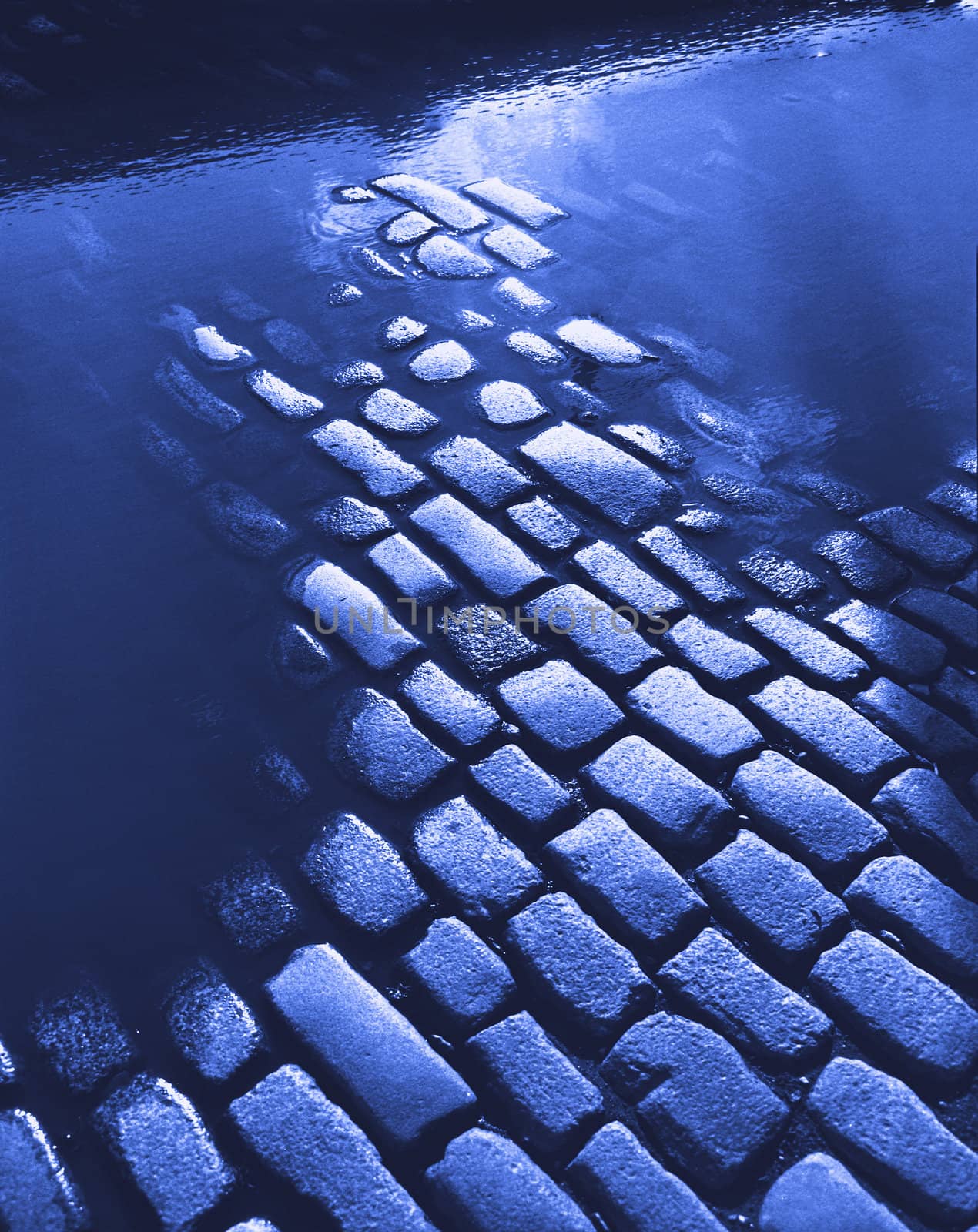 cobblestone road with water puddles in blue tones