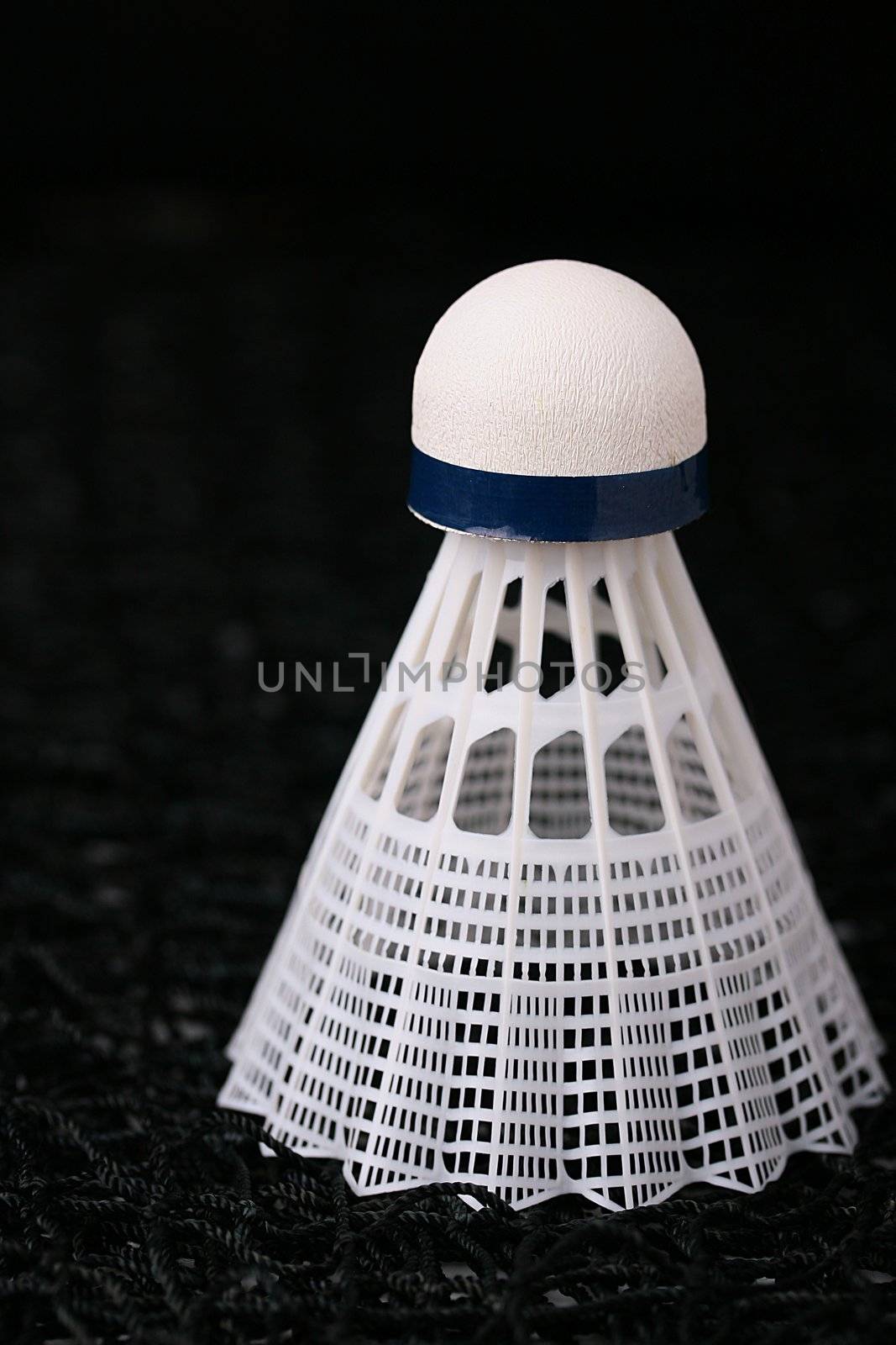 Close-up of a white synthetic shuttlecock on a badminton net.