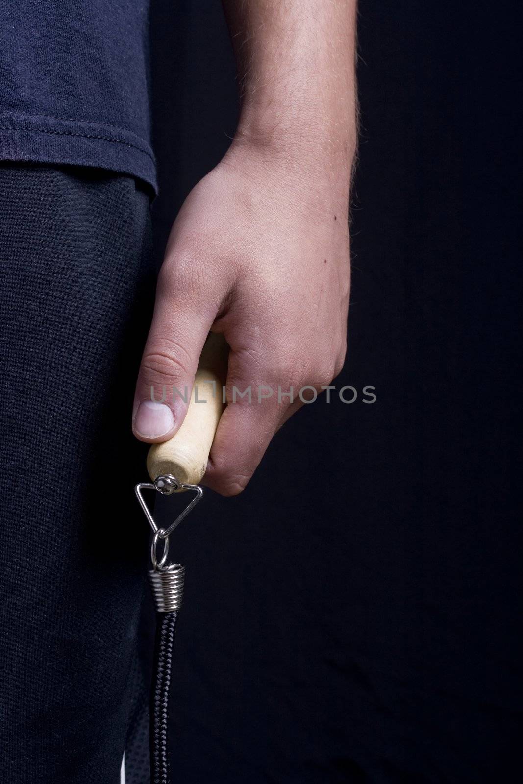 Human hand holding a jump rope on a black background.