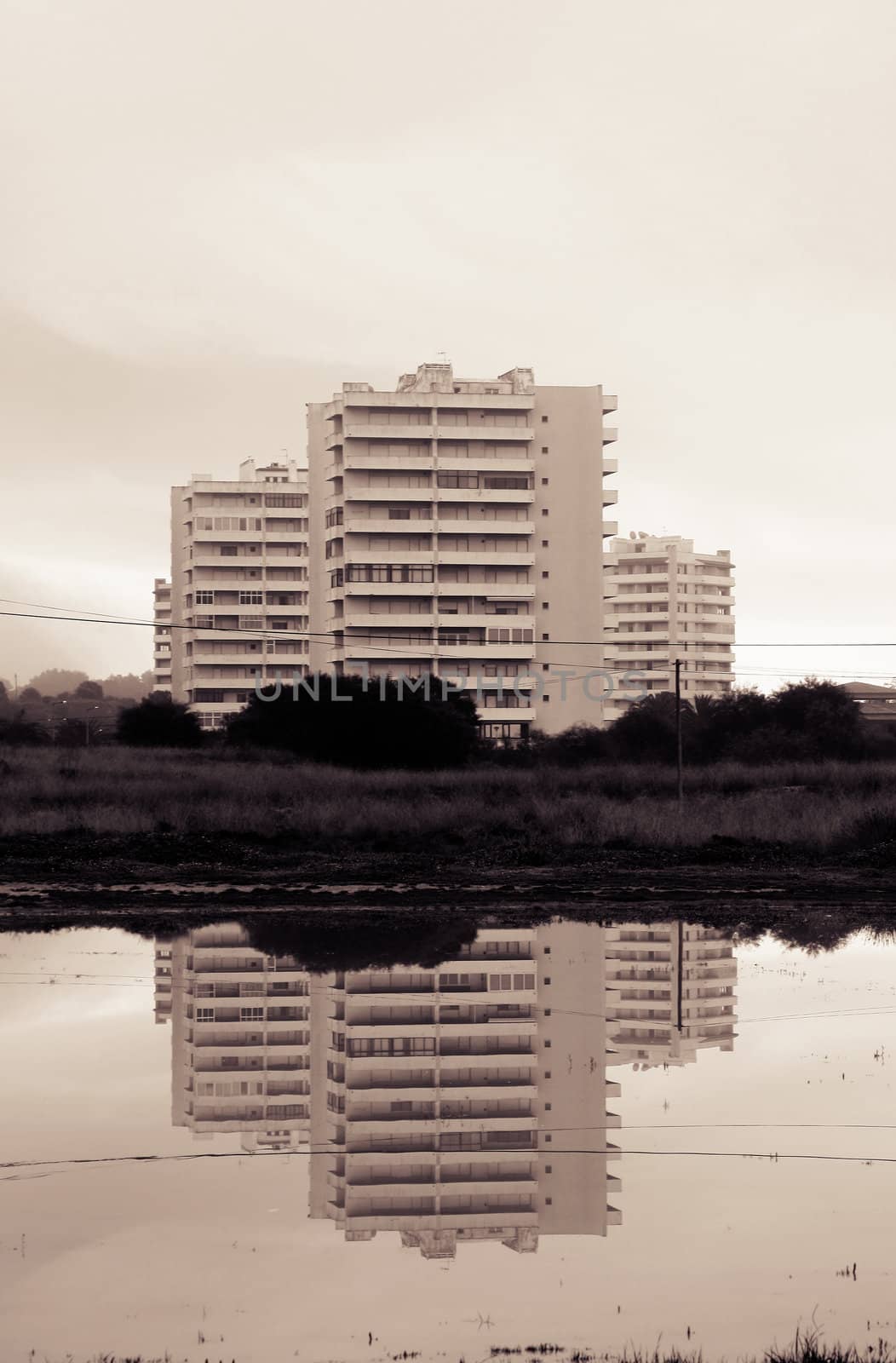 Three tall buildings creating a reflection mirror on the water.