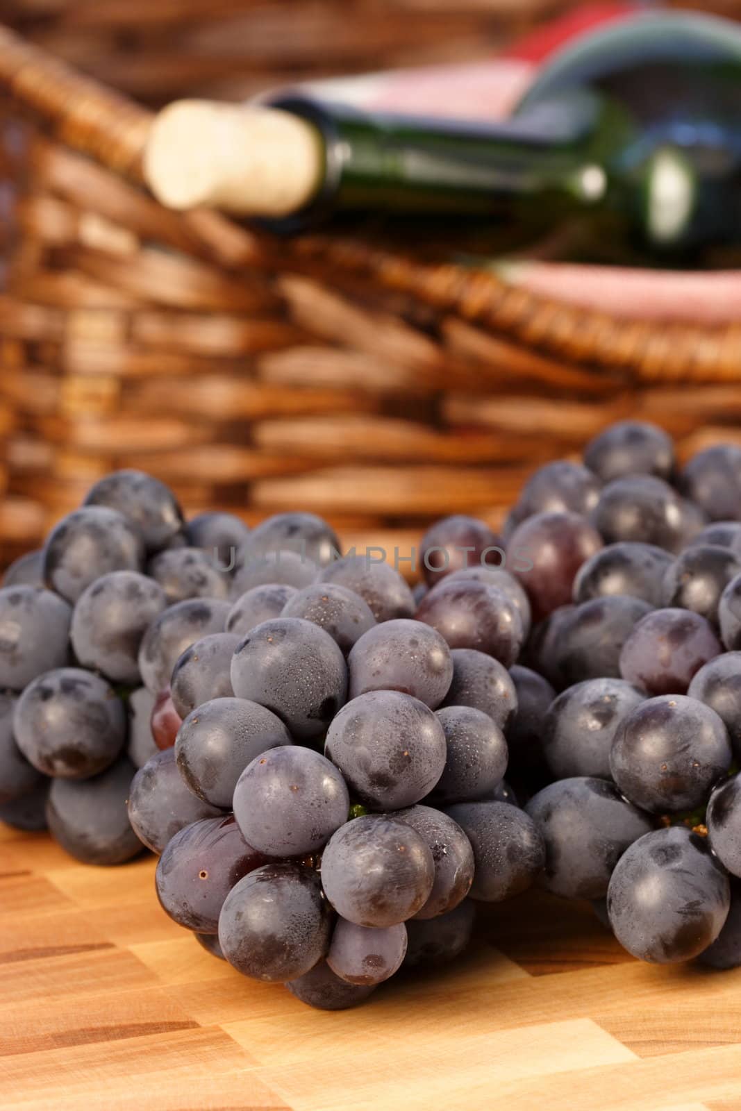 grapes on fine wood cutting board with red wine and bread basket on background 