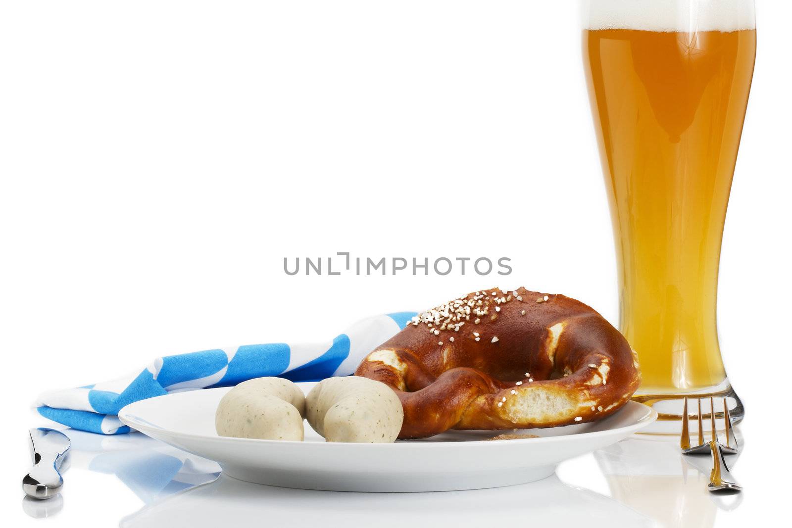 bavarian veal sauages on a plate with beer, pretzel and bavarian towel on white background