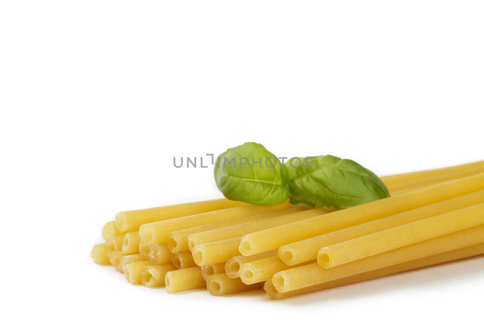 raw macaroni with basil on white background