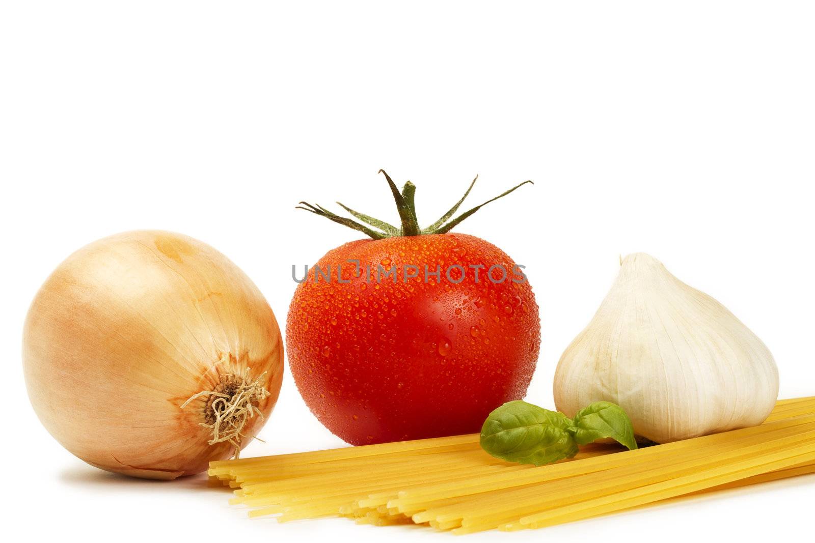 raw spaghetti with tomato, basil, garlic and onion on white background