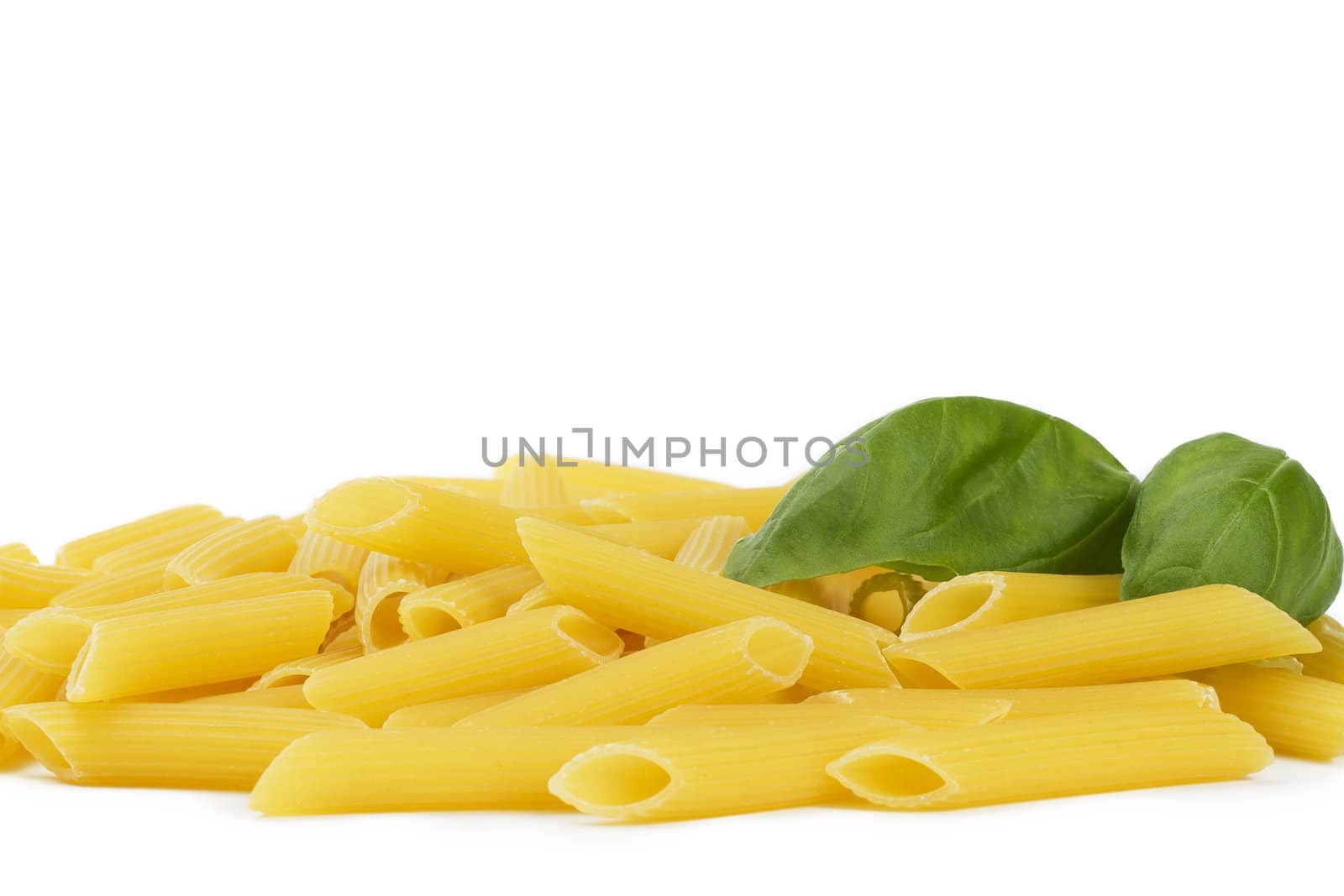 some raw penne rigate with basil on white background