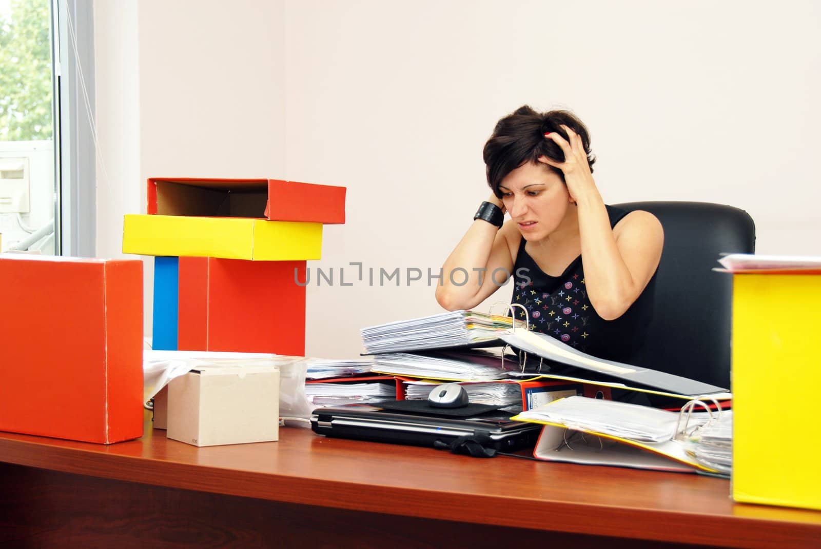 despaired stressed woman sitting at desk overloaded with work holding her head