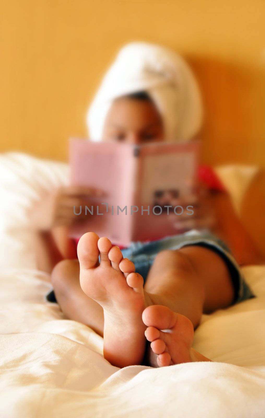 relaxing teenage girl reading  book after shower focused on feet