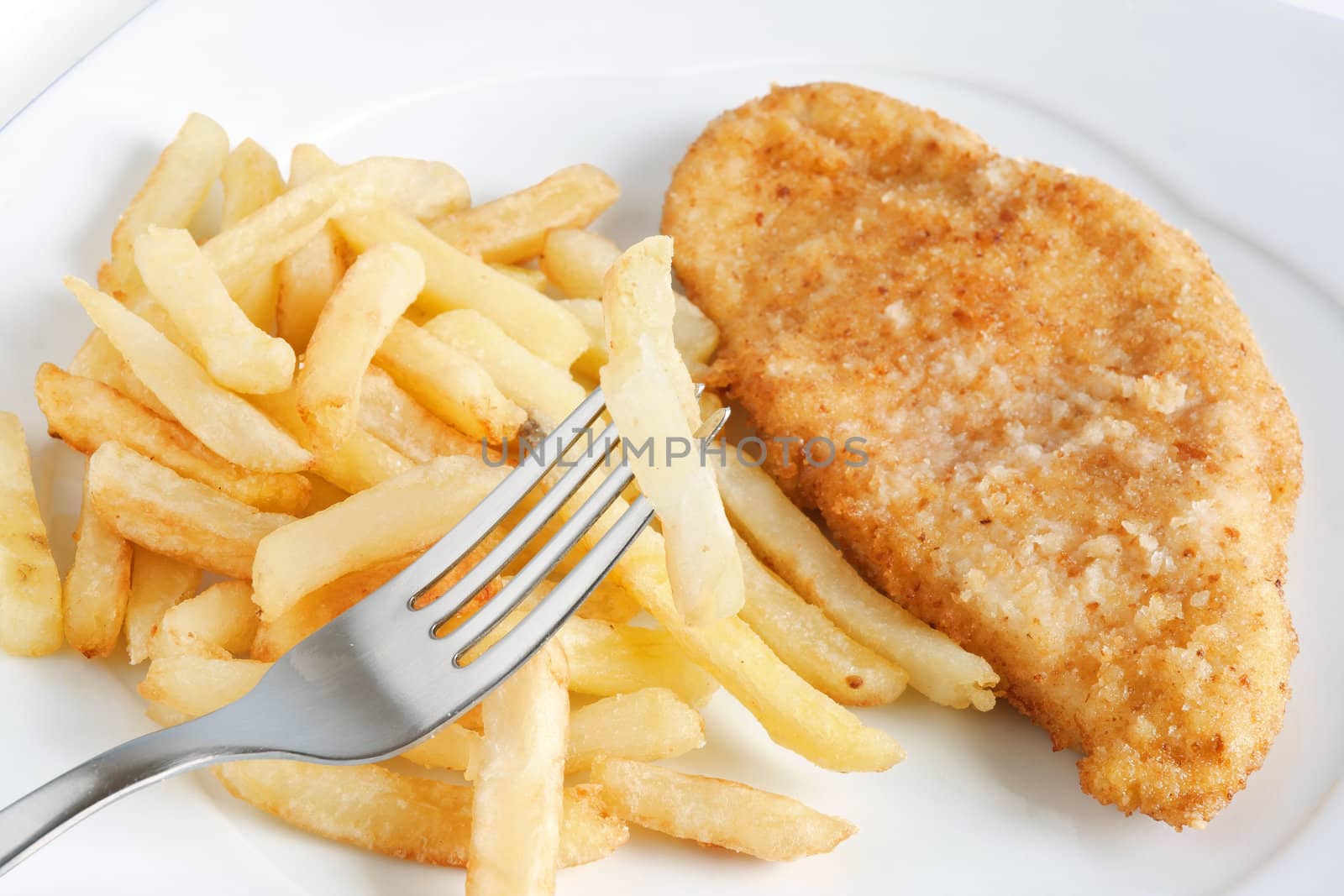 detail of fried potatoes and chicken with fork isolated on white background