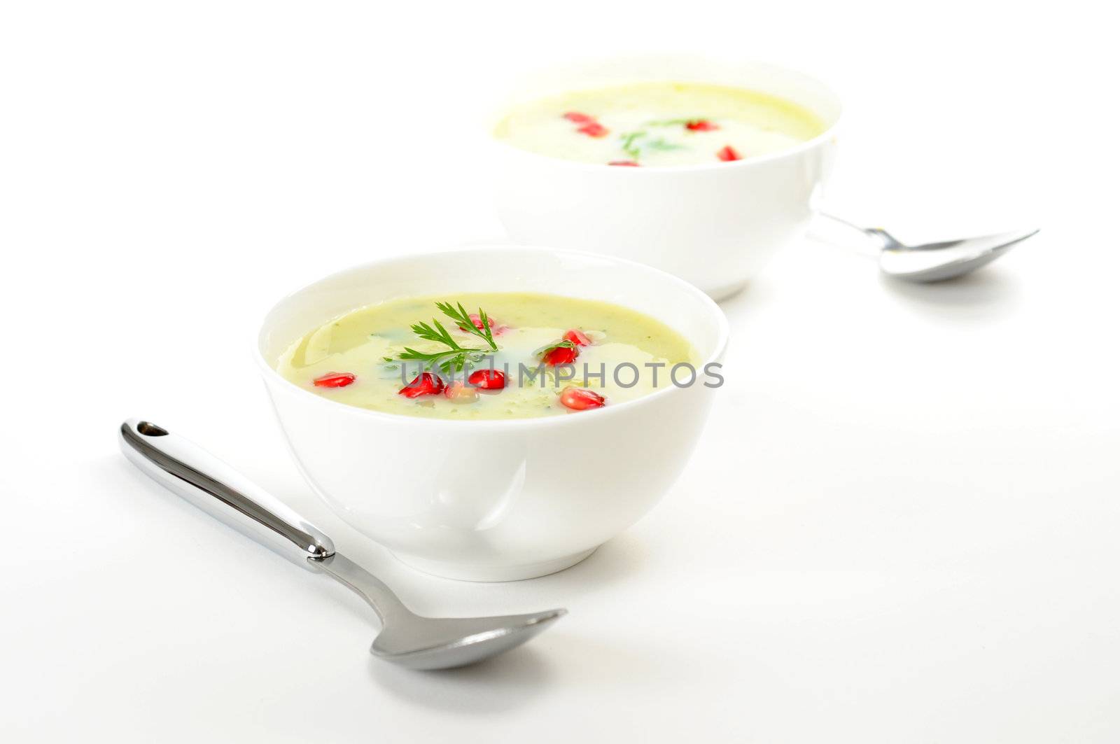 Bowls of health broccoli soup garnished with pomegranate.