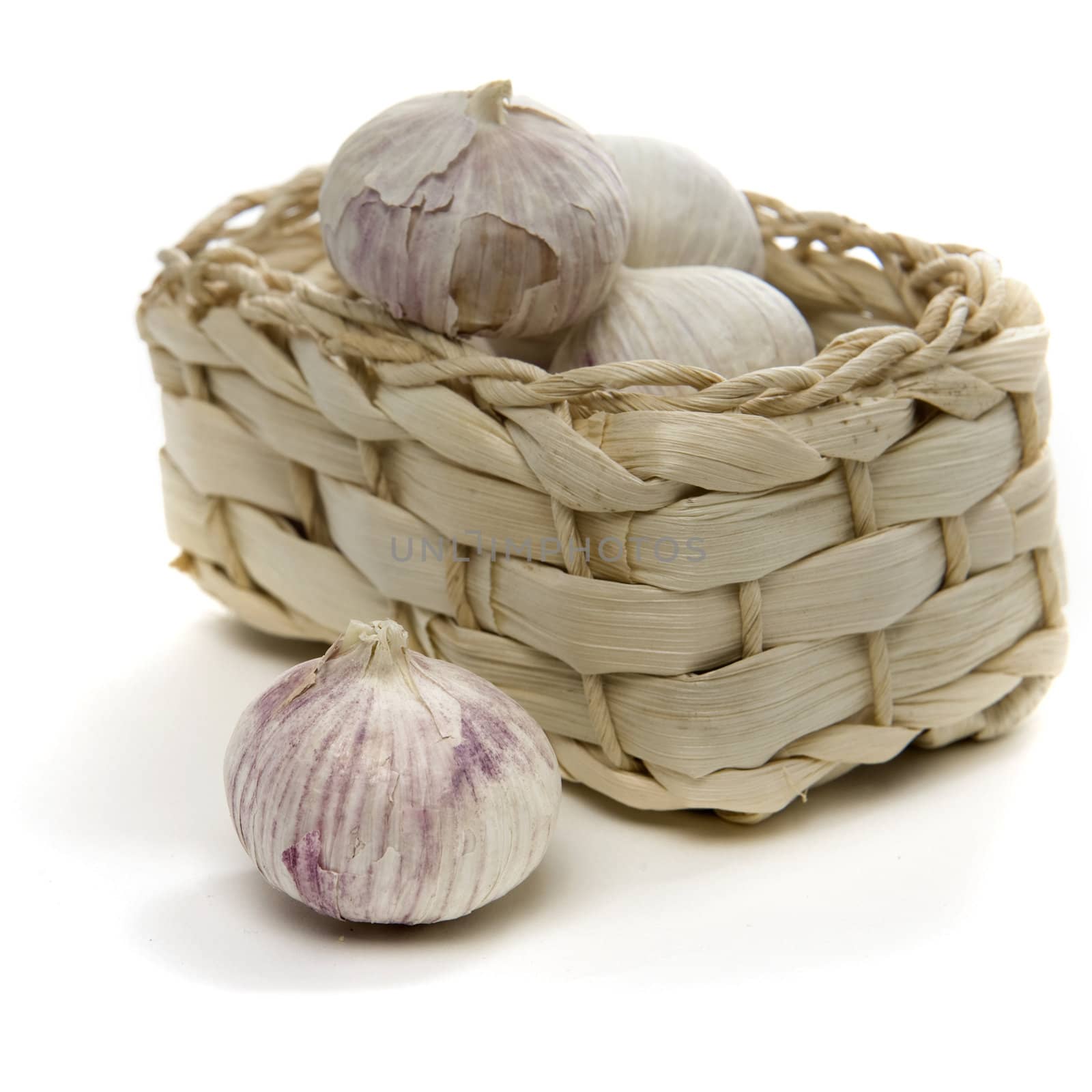 a lot of garlic in a basket on a white background